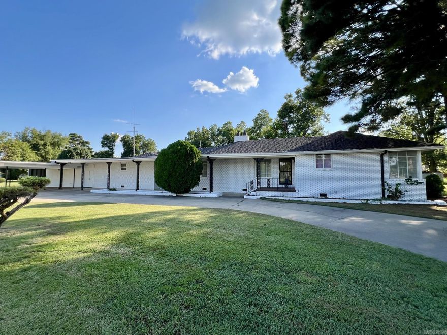 One level 4 bedroom, 2 bath, white brick home with lots of hardwood flooring, large windows, spacious rooms and storage space. The home is a split plan and has a formal living room with cove lighting and gas log fireplace which adjoins a large dining room with antique chandelier. The kitchen is full of beautiful metal cabinetry which has been professionally painted a light neutral shade. It has an electric cooktop surrounded by bar area, built-in convection wall oven and microwave, and a large stainless sink and built-in countertop blender. The workshop is under-roof and is heated and cooled separately from the home with its own mini split system and wood stove. Guests can gather in the game room around the bar, or play a game of pool. The primary suite is large and has a walk in closet and bathroom with double vanity. The 3 other bedrooms are on the other side of the home in a private hall and share a vintage tiled bathroom with a separate shower and tub. Home also has working security system. There are three storage sheds in the extremely private backyard, along with a storm shelter and large covered patio.