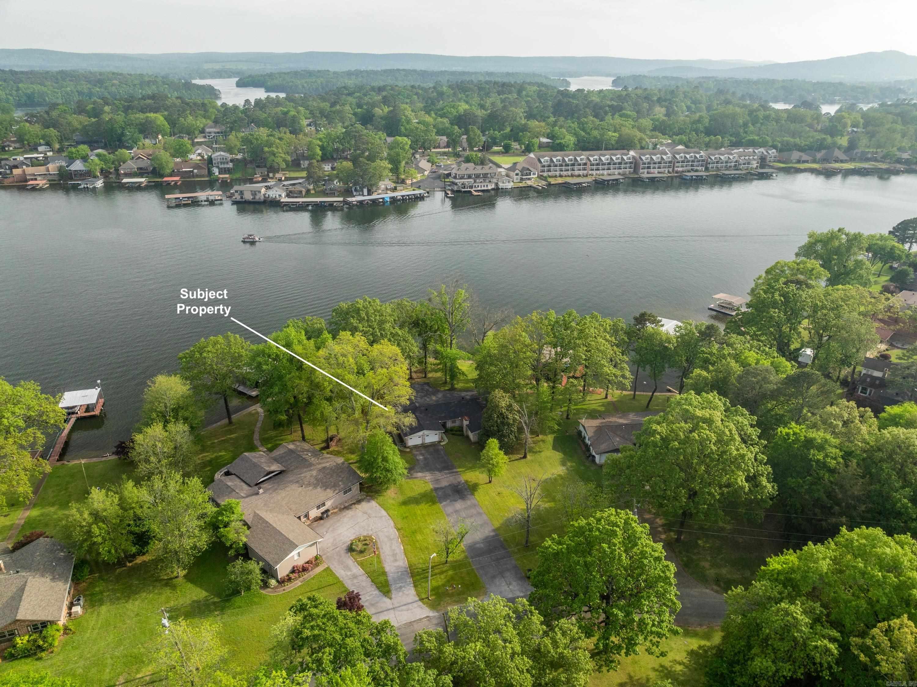 Priced LESS than appraised value! Gorgeous wide-open views to Main Channel from this level Lake Hamilton property. With its rounded 156 feet of frontage on the lake, it darn near feels like a point. The panoramic view is breathtaking. A little over 3/4 of an acre, the deep lot is roughly 156x231. Single story lake home is 3079sf with a brand-NEW ROOF. Great bones on this vintage property but value is primarily in land. Bring your artist's palate and your creative designs to make this stunning property into your dream home or vacation getaway. No flood insurance required of seller.. Entergy says frontage allows for a 2-slip boat dock. See Agent Remarks.