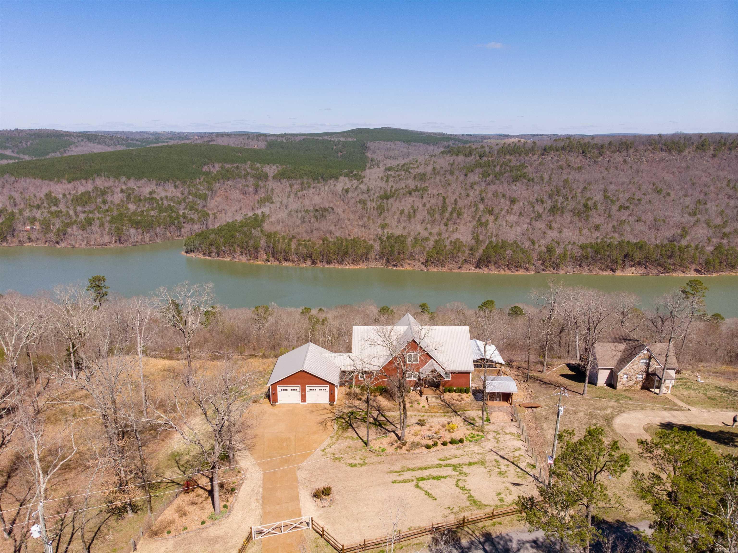 This Custom Home Has It ALL – Lake Views, Luxury, and Space! Tucked behind a gated entrance, this stunning home offers panoramic views of Greers Ferry Lake and an unbeatable combination of style and comfort. From the moment you arrive, you’ll be captivated by the setting and thoughtful design throughout. The gourmet kitchen features granite countertops, a Viking gas stove, and a Viking refrigerator – a chef’s dream. The spacious family room boasts vaulted ceilings, hardwood floors, and a beautiful fireplace. The main-level Primary Suite offers a peaceful retreat, while the downstairs area functions as a complete second living space with a game room, large bedrooms, and a full kitchen – perfect for guests or entertaining. Step outside to an expansive wood deck ideal for taking in breathtaking sunsets. The outdoor kitchen, complete with an additional fireplace, sets the stage for unforgettable gatherings. Additional amenities include a two-car garage, storm room, and whole-house generator. Let’s take a look!