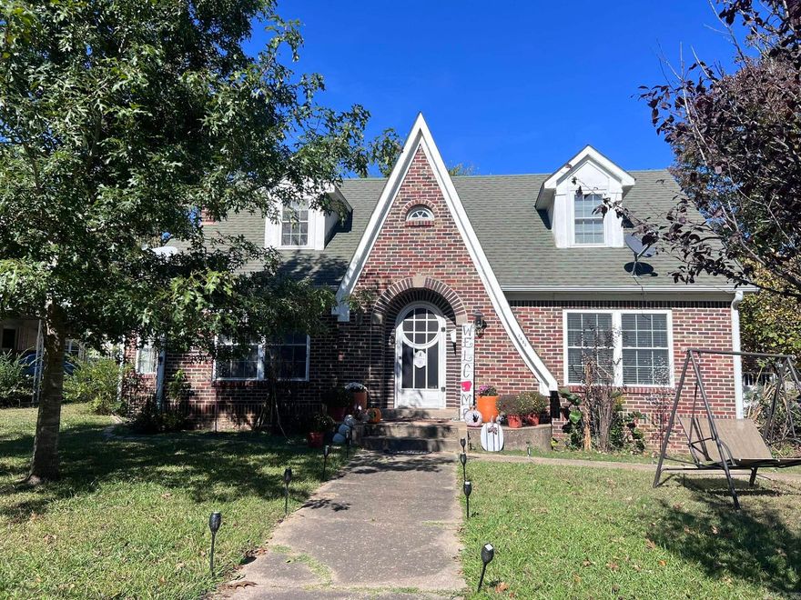 Charm abounds in this beautiful historic home in the city of Mena on over an acre of land that features original hardwood floors! Tudor revival style has lots of storage and plenty of room. The living room has a gas log fireplace as its focal point, plus an extra room that can be used as an office or converted to another bedroom. Bright, sunny dining room leads into the kitchen which features granite countertops, stainless appliances, under counter lighting, microwave, refrigerator and new flooring. Downstairs is a bedroom with built ins and its own private bath. There is also a half bath in the hallway, conveniently located near the back entrance. Up the stairs are two large bedrooms that share a full bath. Unique alcoves add to the charm and style of these spaces. A sliding door can be pulled shut to close off access to the stairs. Bright laundry/sunroom has a view of the expansive backyard which has a wooden privacy fence. Beyond that is another half-acre that has so many possibilities. 2-car garage, concrete, nice patio area to enjoy the seasons. New roof and screens will be coming soon!