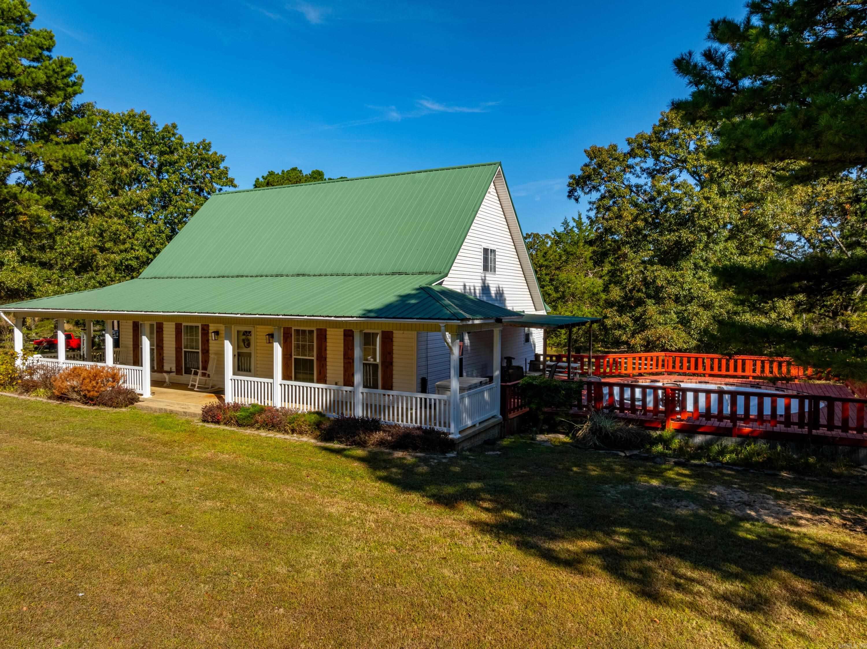 This gorgeous 3 bedroom, 2 bathroom, farmhouse-style home sits on 5 +/- picturesque acres and features a charming wrap-around porch on three sides, perfect for relaxing and taking in the peaceful surroundings. Off one side, you'll find a deck with a swimming pool, offering an ideal space for entertaining or enjoying those hot summer days.As you approach the property, the home's metal roof and scenic pond out back add to its curb appeal. When you step inside, you're welcomed by a grand foyer with stairs leading to the second floor. To the side, the living room opens up to a dining area filled with natural light, thanks to the many windows. Adjacent to the dining room is a spacious, farmhouse-style kitchen with an eat-in bar, perfect for casual meals or gathering with family.The kitchen connects to a convenient laundry room that leads to a spacious garage. Wrapping around the hallway, you'll find the primary suite, which is exceptionally large. It includes a walk-in closet and a luxurious primary bathroom featuring his and hers sinks, a large soaking tub, and a walk-in shower.Upstairs, there are two more bedrooms and a full bathroom, making this home ideal for a family.