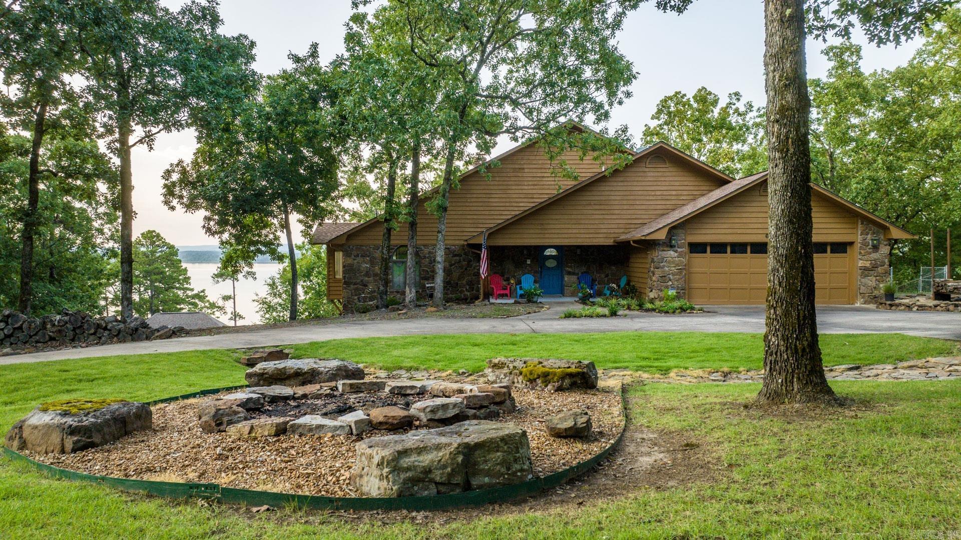 LAKEFRONT! LAKEVIEW! Huge windows! Luxury on "Big" water at pristine Greers Ferry Lake just east of "The Narrows and Bondair". Gated circle drive, warm, welcoming family lakehouse. A dream for entertaining & for lifetime family experiences! Split to rear the main level lives as a 1 level for owners with the primary suite, expansive primary bath, great room, oversized DR, inviting entry, gas starter WBFP, chef's kitchen w/ fantastic wrap around bar, powder room, utility room & a deep deck that spans the width of the home. The lower level is a guest's dream with 2 large ensuite bedrooms & custom full twin sized built-in bunks, a second super spacious living room, a kitchenette & 2 incredible screened porch lanai's with full size outdoor daybeds. Deep, attached 2 car garage. The property offers a fully fenced backyard, a wide concrete path for side-by-side access to the beach, tritoon beach parking, a deeper water anchor for surf boats, and a front yard fire pit and rock creek, all ideal for dreamy nights by a cozy fire underneath the stars! Lacey's Marina is a 5 min ride by boat and about 10 mins by car offering convenient and easy boat housing. NEVER RENTED but VRBO turnkey ready.