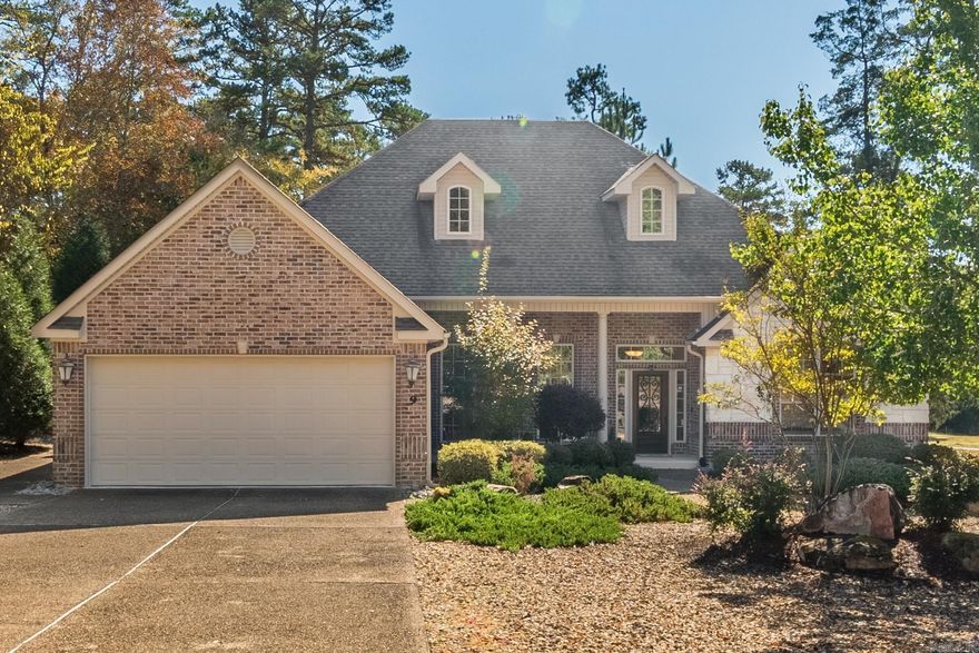 Elegant golf-course living awaits in this stunning stone-and-brick home on Balboa Golf Course in Hot Springs Village. Built in 2007, this 3-bedroom, 3-bath residence combines timeless architecture with gracious design. A lovely front porch and twin dormer windows set a welcoming tone, leading into light-filled interiors with soaring ceilings and expansive transom windows that capture sweeping fairway views. The great room’s dramatic fireplace anchors the open plan, flowing into the dining area and chef’s kitchen featuring granite counters, stainless appliances, double ovens, and a generous breakfast bar. A versatile second living area offers space for a formal dining room, office, or den. All bedrooms are generously sized; two with ensuite baths. The luxurious primary suite overlooks the course and features dual vanities, a soaking tub, and a walk-in tiled shower. Large walk in closet includes built-ins. Crown molding throughout tops off the elegant ambiance.  Laundry with sink and storage plus spacious two-car garage including a separate golf cart bay with its own entrance. Large patio with fans complete the perfect indoor-outdoor living home with panoramic golf-course views.