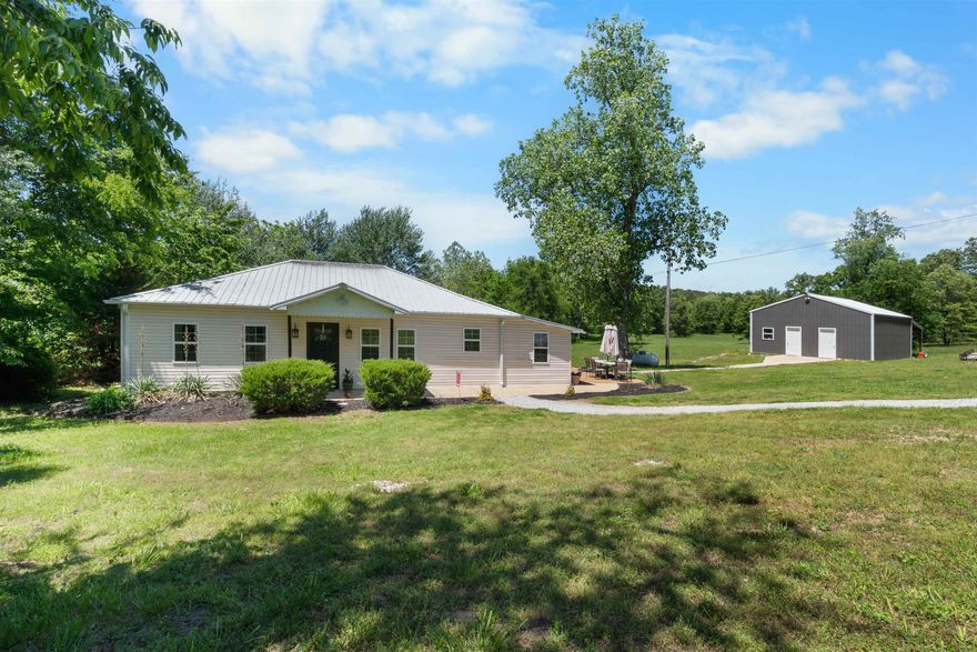 This beautiful 2 bedroom, 2 bath home offers the perfect blend of comfort, functionality, and country charm. Situated on 13.1 gorgeous open acres with a year-round creek. Inside, you’ll love the open floor plan featuring a spacious living area with a gas fireplace. The kitchen has custom hickory cabinets, a breakfast bar, and an open flow into the dining area. The master suite includes an attached full bath with a walk in tile shower. The guest bedroom is spacious with easy access to another full bathroom. The mudroom/utility area offers fantastic space for an office or 3rd bedroom option.  Outside is a back patio, a 32x26 shop fully insulated with a finished out area complete with a full bathroom, plus a garage/workshop space with a lean to attached for additional storage.  With all open usable acreage, stunning pasture views, and a year-round creek running through the property, this one of a kind property is perfect for a hobby farm!