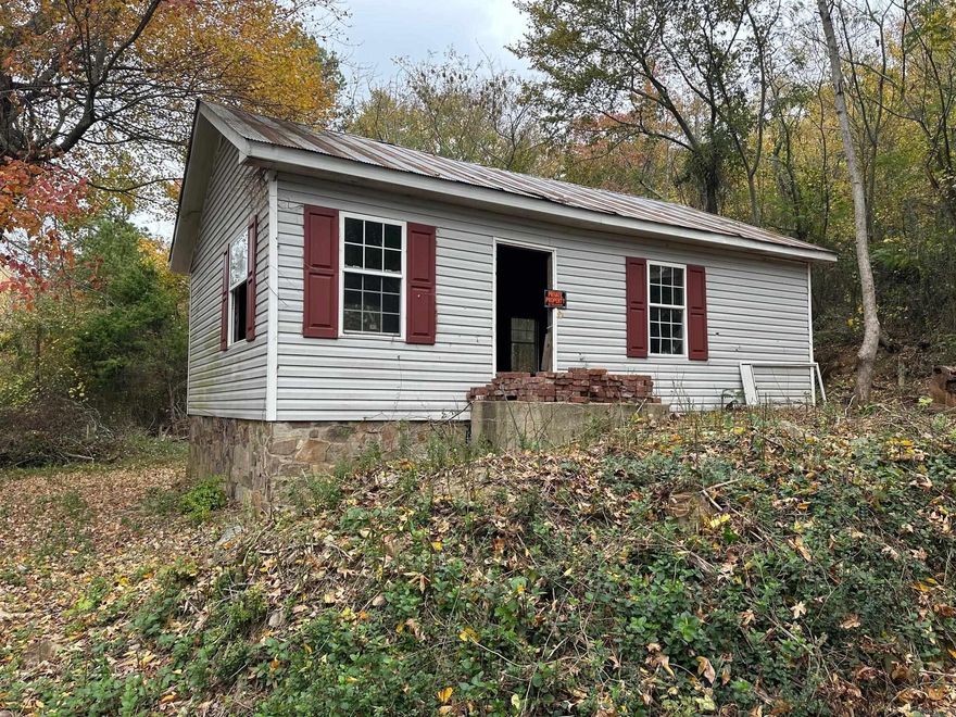 This house sits high on a hill on a corner lot, tucked away from any traffic.  The shell of the home is ready for you to make it your own!  Tin roof and a rock foundation give a country feel.  City sewer is ready for connection, city water is available but not connected.  Come check it out!