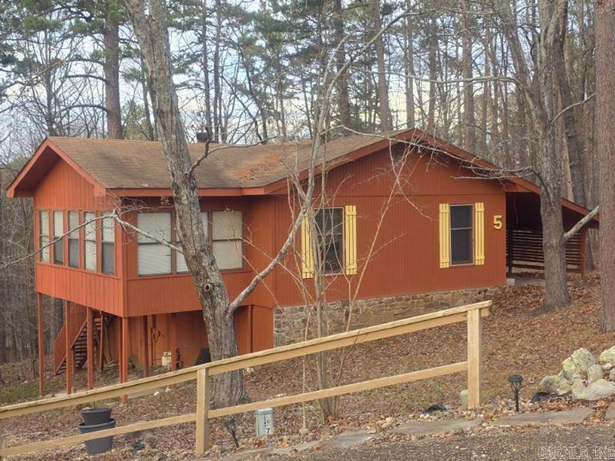 Nestled in the quiet, wooded Cartagena neighborhood of Hot Springs Village, this charming 1974 cottage offers a peaceful retreat. Featuring an open-concept living and dining area with vaulted ceilings and a central stone fireplace, the home maximizes its 1,040 square feet for a spacious feel. Enjoy the surrounding nature from the large back deck or the native Arkansas landscaping. This 2-bedroom home is perfect for those seeking a low-maintenance lifestyle or a weekend getaway near the West Gate, offering easy access to the village's world-class golf, lakes, and hiking trails