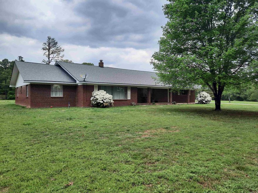 Enjoy country living just minutes from town.  This spacious brick home offers a serene setting on almost 5 acres of nice laying land, a perfect mixture of cleared land and trees, with mature shade trees lining the country driveway.  With plenty of elbow room, open concept on inside and large front and back porch to set and enjoy quiet and relaxing times. Oversized attached garage plus a large, detached shop/garage. This home has so much to offer, it's the perfect place to call home.