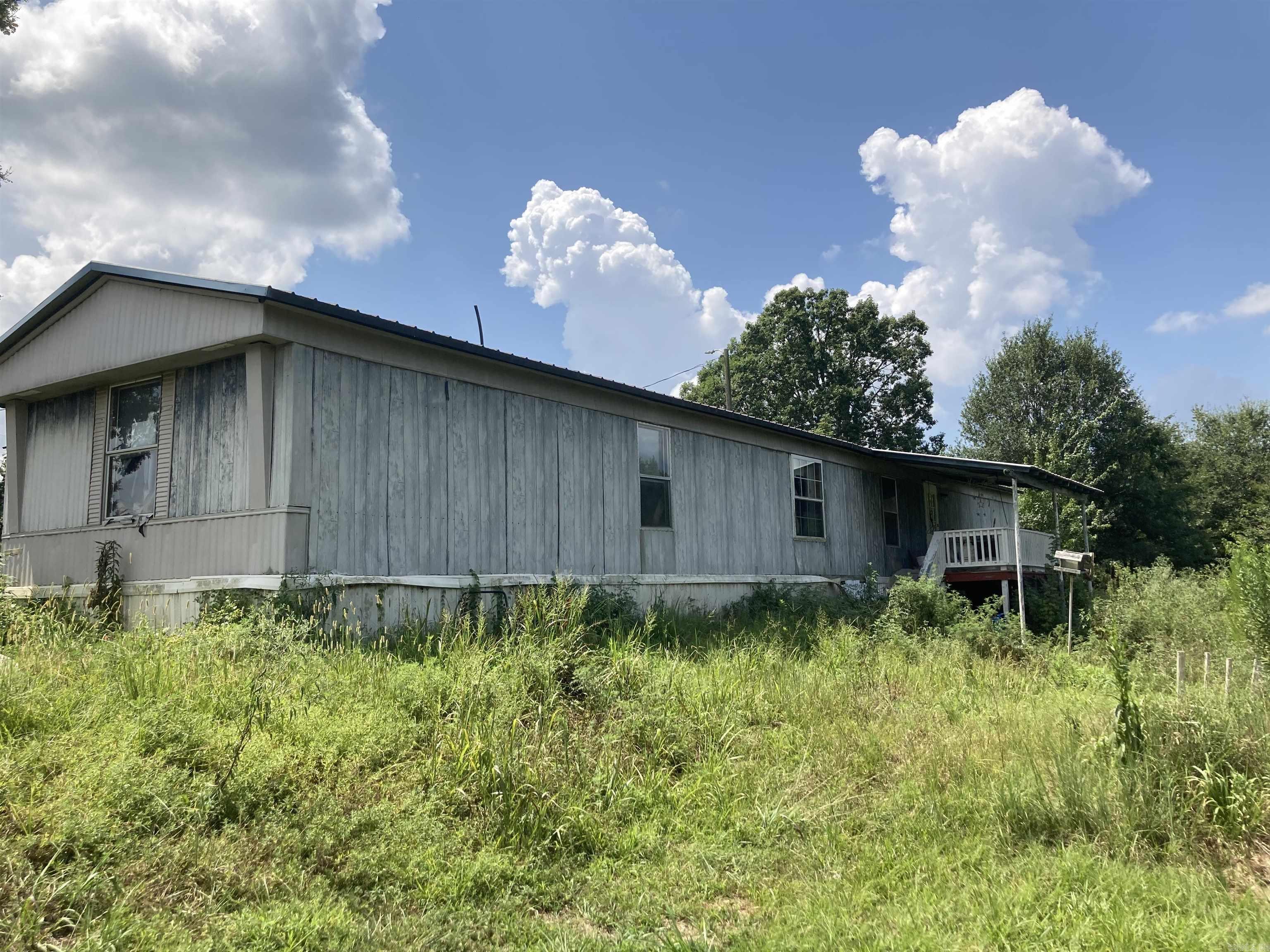 PRICED TO SELL!!! So much potential on this acreage! 3bed, 2bath spacious manufactured home, just needs a little TLC and being sold AS-IS, but you can't overlook all the extras with this property! Nestled on a corner lot with 12 acres m/l, a pond with small fishing deck, extra storage building and privacy. Electric available on two sides of the property as with high flat ground, so additional building sites are options as well as subdividing in the future! This will not last long!
