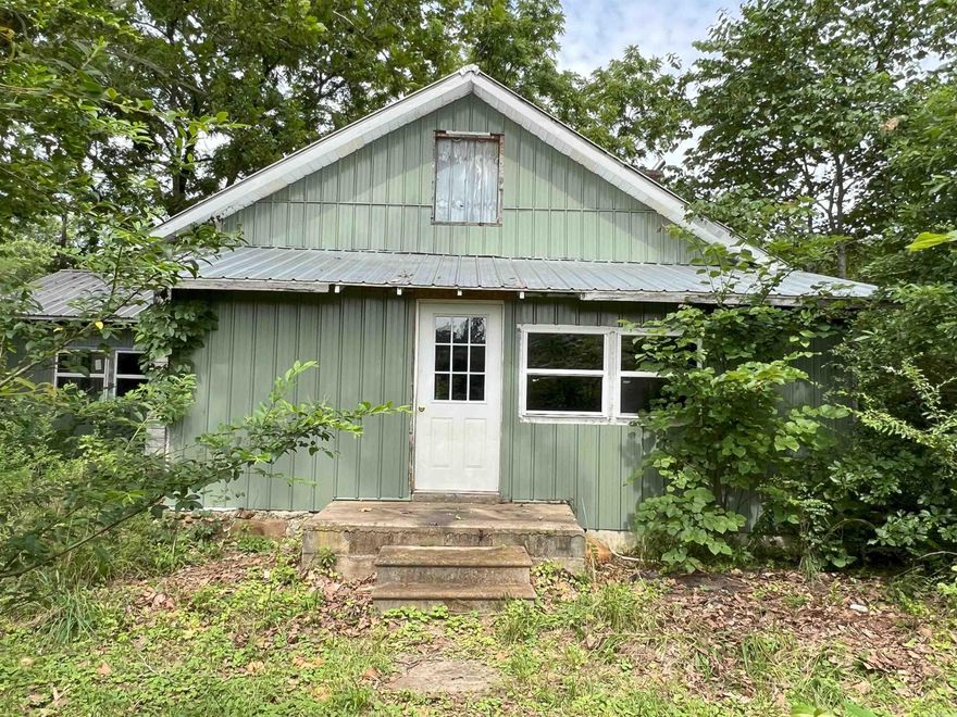 This house is a "builder's special," currently undergoing an extensive remodel, offering a blank canvas for your vision. One of its most striking features is the grand stone fireplace, serving as an inviting central focal point in the living area. This charming home also boasts a versatile bonus room upstairs, as well as attic space for additional storage. A New metal roof and siding have already been installed. Included on the property are two electrical boxes, ensuring ample power supply for your needs, and two wells that provide a source of water. A gated entry and fencing secure the lush pastureland, which produces good hay ready for livestock, and a small pond. Additionally, there is a 30x30 metal shop with a concrete slab. The old mobile home holds no value.