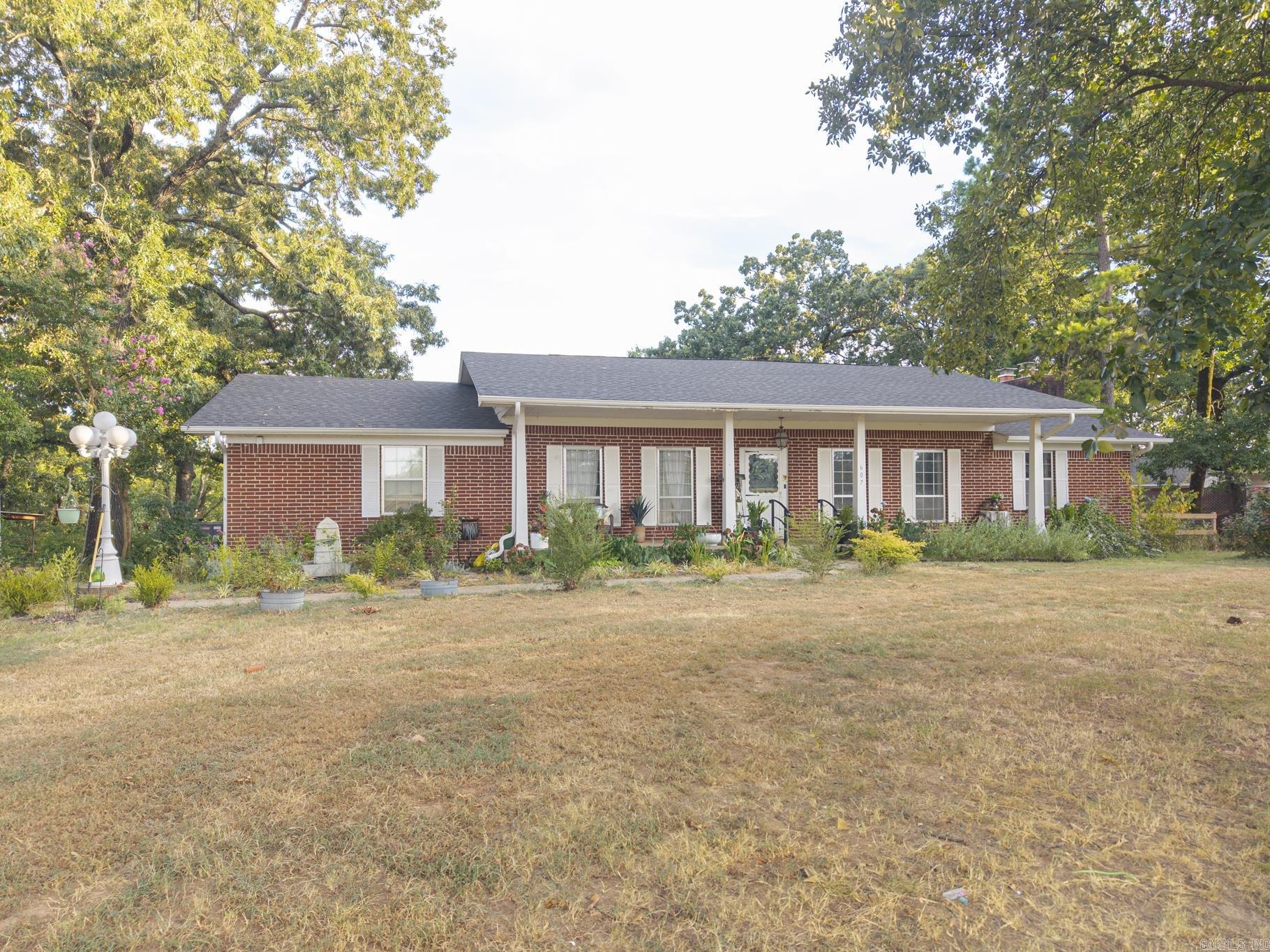 This traditional-style red brick home, complemented by beautiful white shutters and columns, is situated on approximately 2 acres in Charleston. The property is enhanced by mature trees, including nine fruit trees, and features a rain barrel. Inside, the residence boasts four spacious bedrooms with 3 designated desk areas, and ample walk-in closets, providing generous storage options. The open floor plan encompasses a large living room with a wood-burning brick fireplace, a dining area, and a retro kitchen. An oversized covered patio adjacent to the kitchen offers an ideal setting for evening dinners while enjoying scenic views. The finished basement includes a kitchenette, and wood-burning fireplace, making it a perfect game room. Additionally, a detached workshop equipped with electricity provides an excellent space for a home business or extra storage.