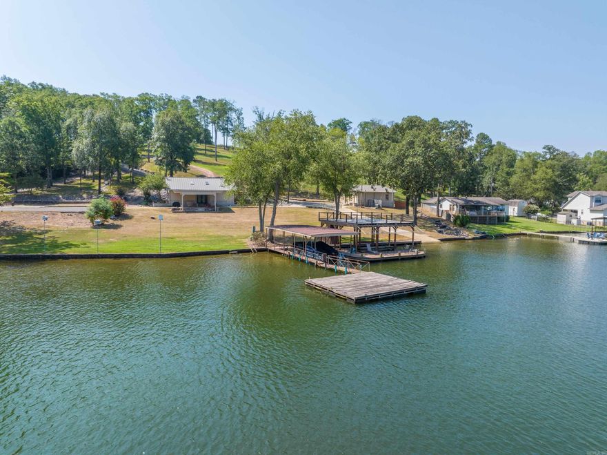 This exceptional lakefront property on the highly sought-after south shore of Lake Hamilton offers a rare combination of natural beauty,development potential, and luxurious amenities. Spanning approximately 4.25 acres with 226 feet of pristine shoreline, the land featuresmultiple building sites both on and off the water, making it ideal for a private compound or a boutique residential development. A naturalwaterfall cascades from the top of the property down to the lake, flowing past exposed rock formations embedded with authenticdinosaur fossils—an extraordinary and unique natural element rarely found anywhere. At the water’s edge, the property is fully equippedfor lakefront living with three covered boat slips, a private boat launch, a large swim platform, and two party decks including an expansiveentertaining area atop one of the docks. The estate is gated for privacy and includes the Pinehill House, a well-appointed residencefeaturing Viking and Sub-Zero appliances, Madrid quartz flooring, a recently updated roof (2023), new skylights and gutters, and a two-car garage with workshop space. A newer high-efficiency AC system ensures year-round comfort. Whether you’re looking for a
