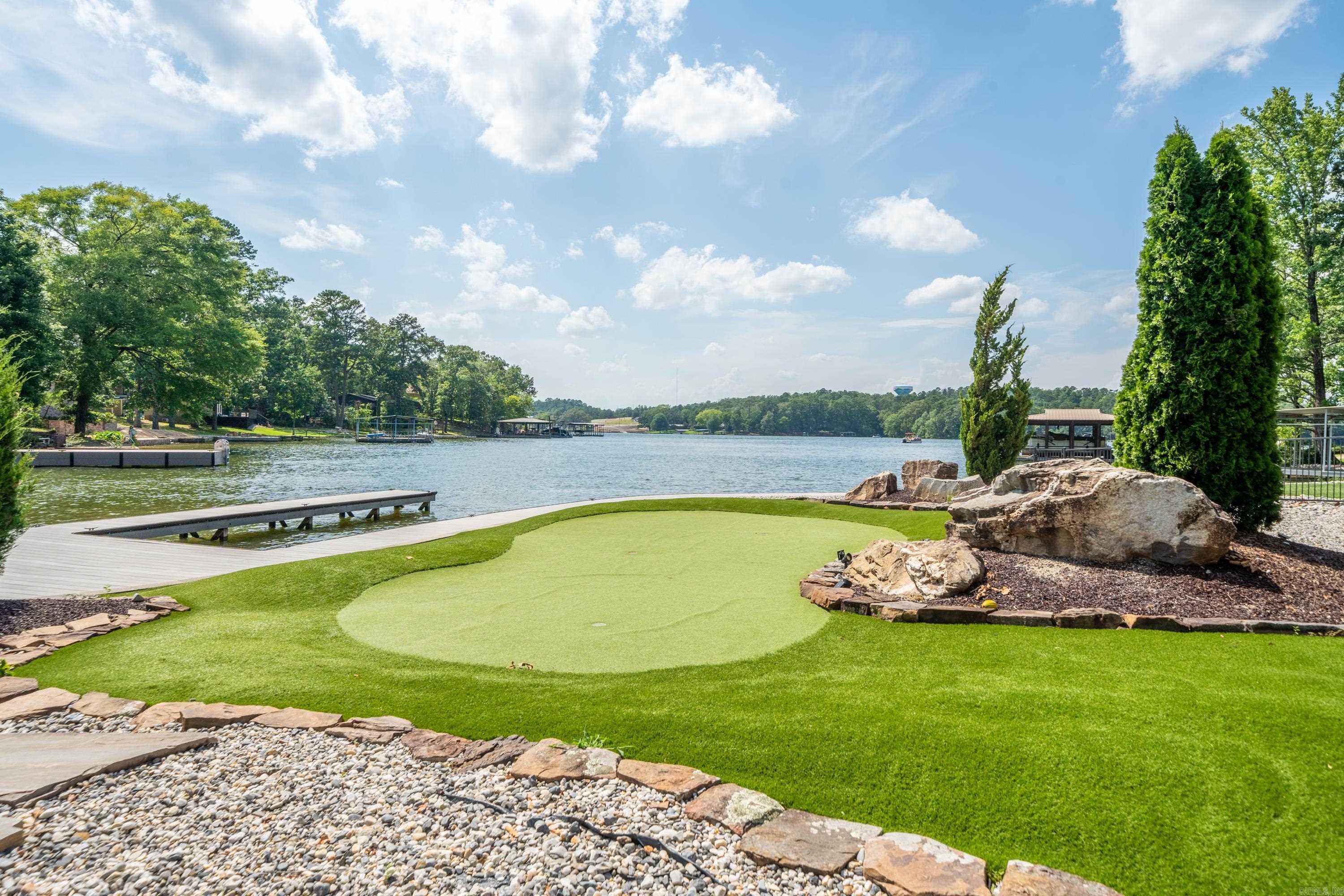 Introducing the epitome of luxury lakeside living on Lake Hamilton at 500 Bayshore. Nestled in the heart of Hot Springs this home offers an unrivaled experience in short-term rental accommodation. Perched majestically on the pristine shores of Lake Hamilton, this property is over 3400 square feet of carefully designed living space, meticulously crafted to exude sophistication and charm at every turn. The residence boasts panoramic views of the serene waters, inviting guest to immerse themselves in the tranquility of lakeside living. With approximately 150 feet of private lake frontage, guests have exclusive access to the shimmering water, where endless aquatic adventures await. A private boat slip offers the perfect launching point for exploring the vast expanse of Lake Hamilton, whether by boat, jet ski or paddleboard. For those seeking relaxation and rejuvenation, indulge in the ultimate in leisure in the hot tub, where the soothing water provide the perfect escape from the hustle and bustle of everyday life. Take in some golf practice on the putting greens, or enjoy the beauty of the beautiful water features. Cont'd in Agent Remarks..