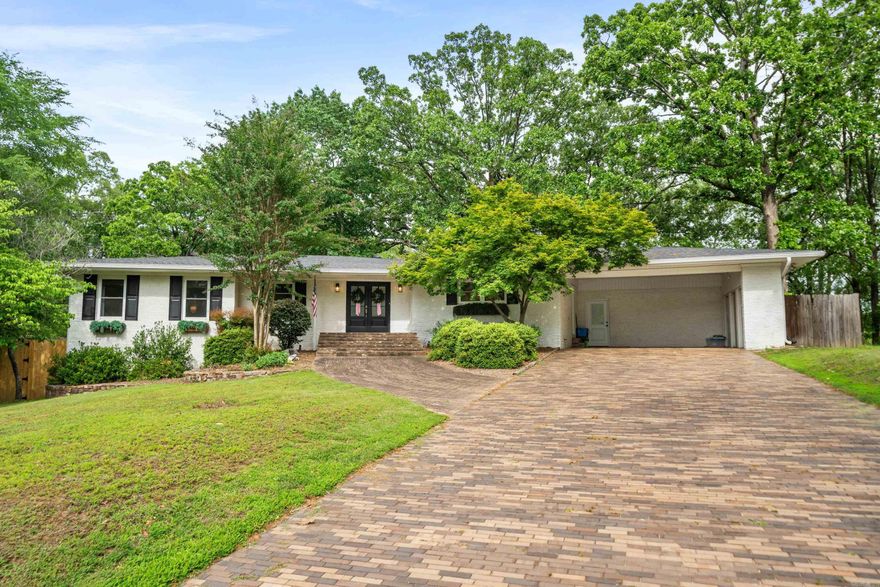 Nestled in the heart of the highly desirable Lakeside School District, this remarkable 4-bedroom, 3-bath home offers a rare opportunity to own a piece of local legacy—the former residence of Verna Garvan, one of Hot Springs’ most influential figures and namesake of Garvan Woodland Gardens. From the moment you arrive, you’ll be captivated by the charm and craftsmanship that define this home. A unique wrap-around exterior built with custom-made bricks sets the tone for the timeless quality you’ll find inside. Step through the front door into a spacious step-down living room highlighted by an impressive floor-to-ceiling brick fireplace and hearth, perfect for cozy evenings or gathering with family and friends. Throughout the main level, original hardwood floors create warmth and character, beautifully preserved yet complemented by modern updates. The kitchen has been fully renovated, featuring sleek cabinetry, solid-surface countertops, and contemporary appliances—ideal for everyday living or entertaining. The home’s lower level offers versatility and privacy, with a second living area, separate exterior access, an additional bedroom and full bath, and tons of storage.