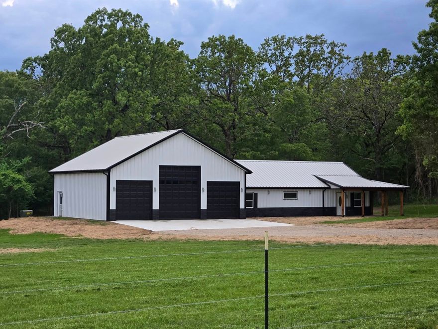 Beautifully constructed steel barndominium with country cedar columns and a wraparound porch situated with a scenic country setting on a  fully fenced 5 acres m/l.   The interior features an open concept highlighted by the vaulted ceiling and kitchen/dining/living great room.   The kitchen features all the extras from the granite countertops, to the island, and the built in pantry and lazy susan.  Master bedroom en suite with private bathroom and ample close space.   This floor plan features a total of 3 bedrooms, and 2 bathrooms, with a 40x40 (1600 sq ft) heated workshop/garage with 220’ electrical service and two 10’ bays and one 14’ bay.   All of this can be a self-sustainable mini farm with both luxury and the convenience of being close to Walmart, Ozarka College, Ash Flat Ball Park, and more….This one is already started.  Call to add your personal touches today!
