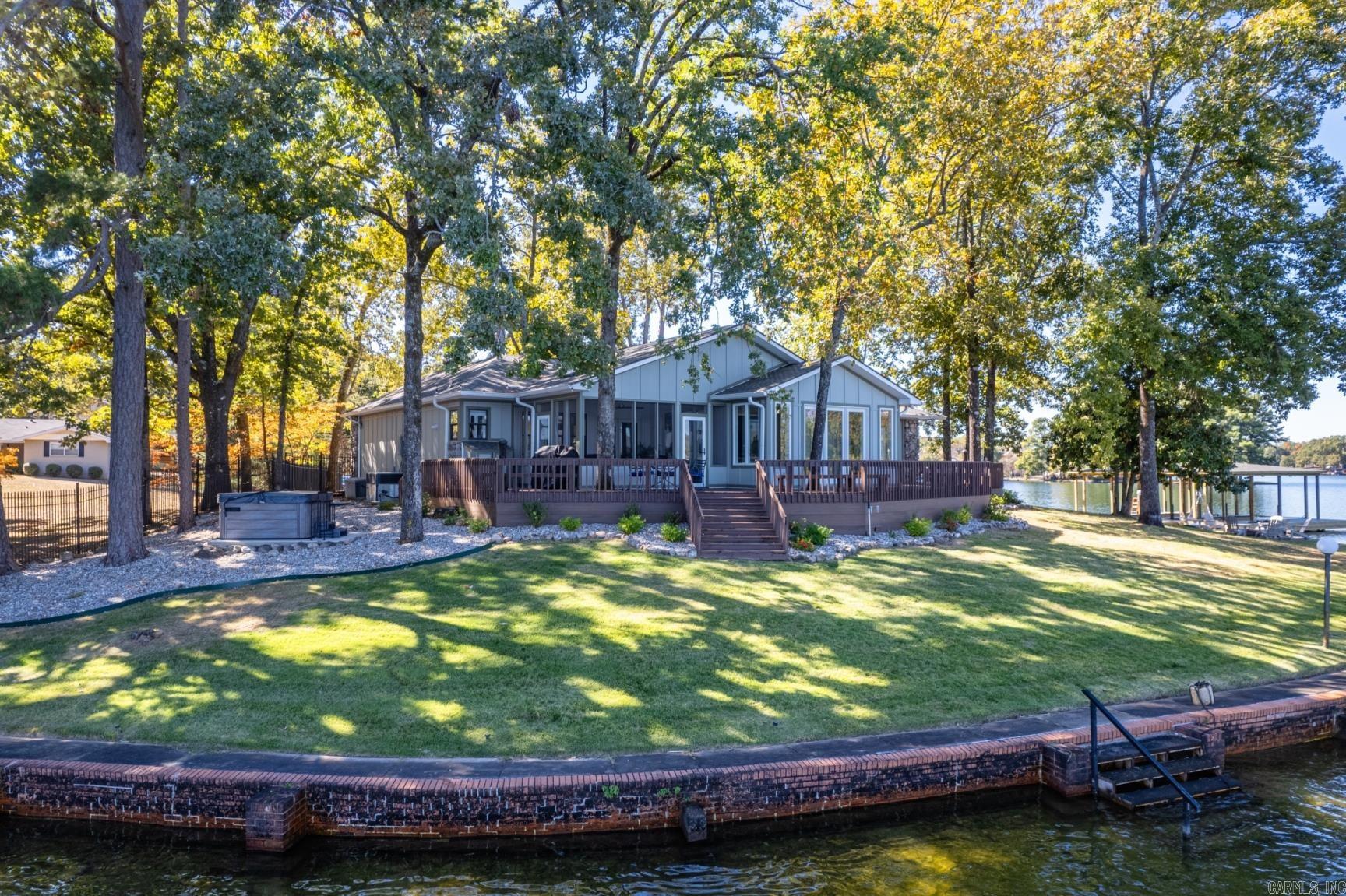 Luxury lake living on the waters edge of beautiful Lake Hamilton. Peace and serenity are yours when you live ON the POINT! This 4 bedroom home has fresh paint inside and out and updated bathrooms plus a new stationary double slip boat dock! This home has it all AND a GUEST HOUSE. From the moment you walk thru the double front doors you'll feel right at home with panoramic lake views of the main channel water. The open floor plan is perfect for entertaining whether you are hosting a backyard barbecue or gathered around the fireplace on game night you're sure to fall head over sunset for this gem. Floor to ceiling windows, low maintenance floors, natural light, large open kitchen, screened sun porch and wrap around deck mean more time to relax and enjoy life. Your guests will enjoy their own little piece of paradise when they stay the night in your guest house complete with a mini kitchen and their own back porch sunset views! Permitted to add boardwalk and swim dock. Call today for your private showing.