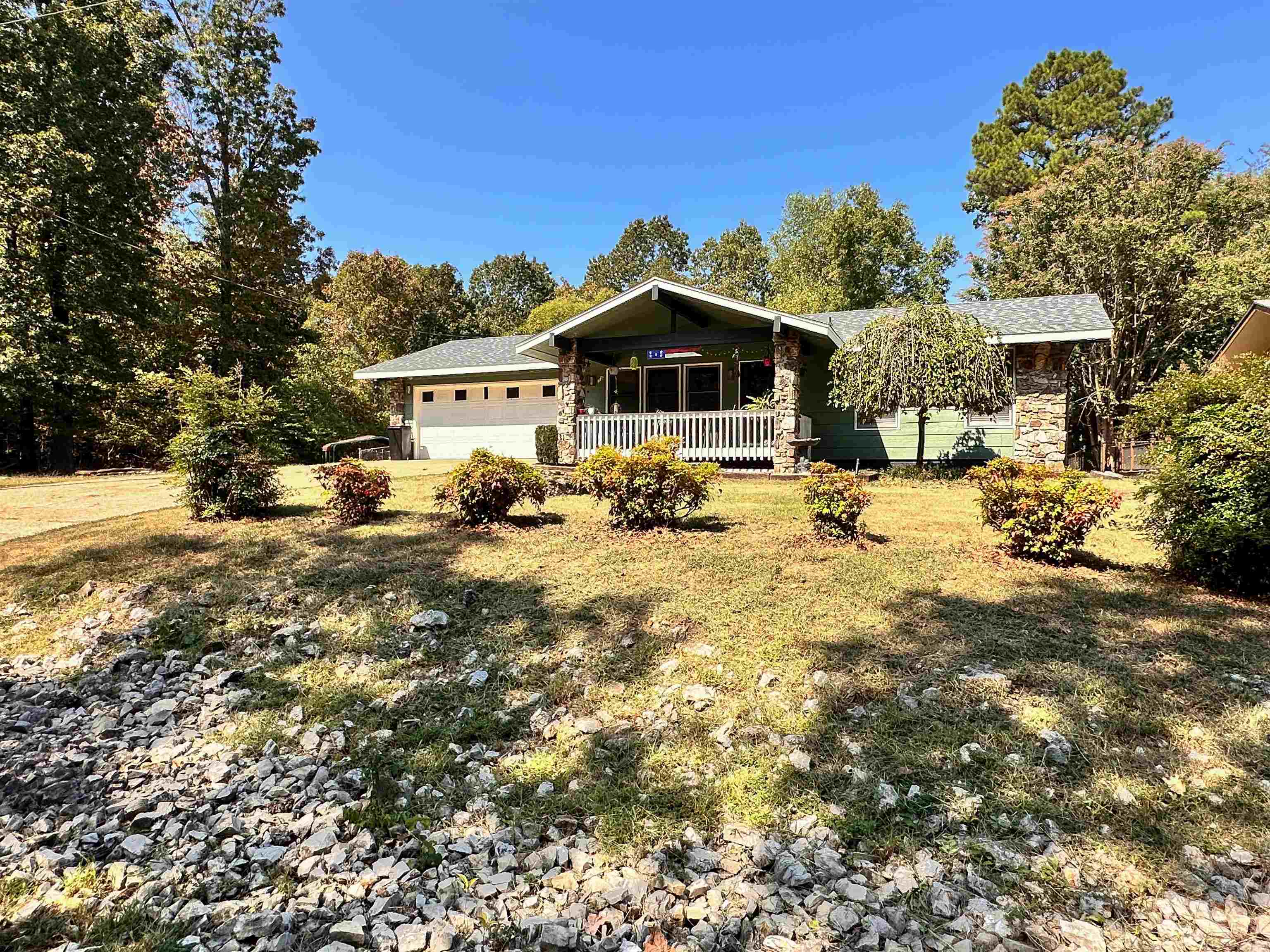 Escape to a serene retreat with this charming 2-bedroom, 2-bathroom home, perfectly situated on two beautiful lots. As you approach, you'll be greeted by a welcoming covered front porch, an ideal spot for enjoying your morning coffee. Inside, the living room beckons with a cozy native stone gas log fireplace, while the adjoining sunroom offers a peaceful space to relax and soak in the natural light. The kitchen is a chef's delight, featuring sleek stainless steel appliances that all convey. The functional laundry room comes equipped with a washer and dryer, and a convenient pantry for ample storage. Step outside onto the back deck to admire your private, chain-link-enclosed yard, and Storage/Work Space, which backs up to tranquil woods, providing a perfect blend of privacy and nature. The attached two-car garage offers both security and extra storage. You can rest easy knowing the roof was replaced within the last year and extra insulation was recently blown into the attic, boosting the home's energy efficiency. This home truly offers a perfect blend of comfort, convenience, and peace.