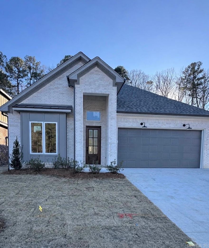 This thoughtfully designed home offers three bedrooms, two full bathrooms, and an additional powder bath, all arranged within a desirable split-bedroom floor plan. Tall ceilings throughout enhance the sense of space and light, while the open-concept layout seamlessly connects the kitchen and dining areas, making the home ideal for both everyday living and entertaining.  The kitchen features a walk-in pantry and flows effortlessly into the main living area, anchored by a gas log fireplace for warmth and character. Both full bathrooms are finished with custom tile showers, and the primary suite is further elevated by a freestanding tub that adds a touch of spa-like comfort.  Outdoor living is equally inviting with a covered patio and exterior fireplace, perfect for relaxing or hosting guests. The property backs up to peaceful green space, offering added privacy and natural views. A short walk leads to a community pool and park currently under construction, providing future recreational convenience right outside your door.