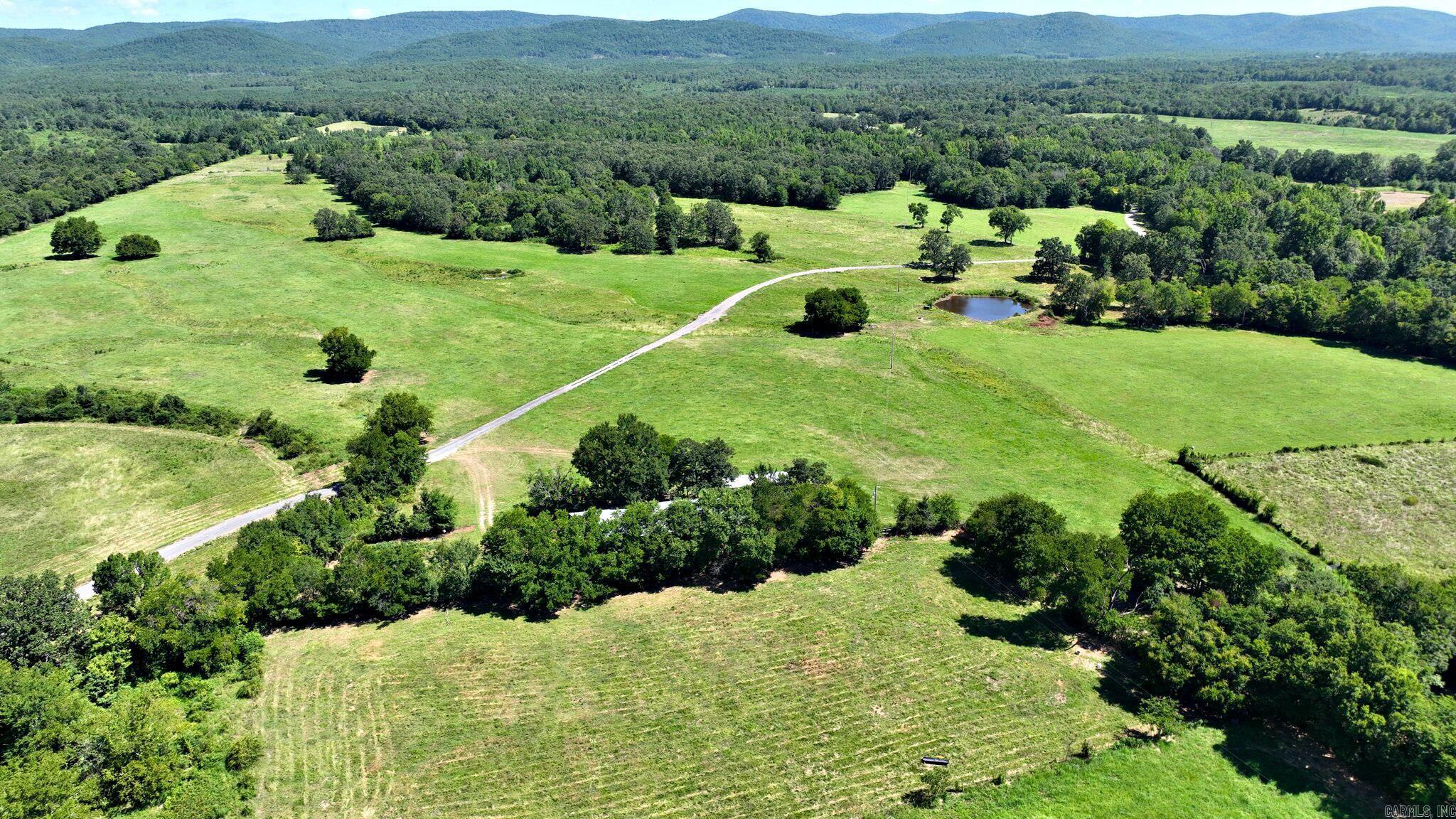 Welcome to a rare opportunity to own 158.74 acres of breathtaking countryside, held in the same family for generations. This stunning tract of land offers a beautiful mix of pristine, level pasture and scattered woods, all set against a backdrop of sweeping mountain views. With an artisan well and spring-fed ponds, water is abundant for both livestock and wildlife. The land is fully fenced and cross-fenced, offering lush, fertile pasture ideal for grazing animals or small-scale farming. A 40x100 barn provides substantial storage or workspace, along with an 18x30 shed that includes an additional 20-foot covered area. Perfect for a private homestead, family retreat, or thoughtful development, this property is conveniently located near popular ATV trails, offering outdoor recreation right at your doorstep. Mobile homes are allowed, and the acreage could be subdivided, providing flexibility for various uses. While the land invites creativity, there are a few protective restrictions in place to preserve its peaceful character—no commercial cattle, chicken, or hog operations, and no RV park development allowed. Portable corral panels do not convey with the property. See agent remarks.