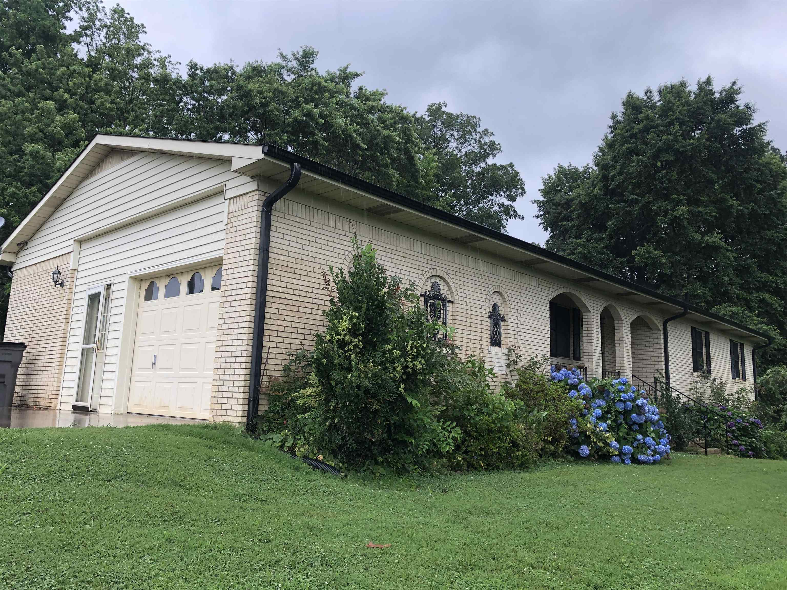 This beautiful all-brick home offers space, comfort, and versatility all nestled on 2.24 rolling acres within city limits. The top level features 1,378 sq ft of well-planned living space with 3 bedrooms and 2 full bathrooms. A welcoming living room opens to the dining and kitchen area, with a nearby laundry room for added convenience. Downstairs, the fully finished walk-out basement offers an additional 1,316 sq ft, creating the perfect space for extended family, guests, or hobbies. It includes a large second living area, a full bathroom, a second laundry room, two bonus rooms that can serve as an office, craft room, or additional bedrooms, and a spacious storage room. An oversized single-car garage provides extra storage space. Outside, enjoy the peaceful beauty of mature shade trees and blooming flowerbeds, perfect for relaxing or entertaining. For those who need a serious workspace or hobby shop, the 28x40 insulated metal building is a dream equipped with electricity, heat, and air, it's ideal for woodworking or other crafts. This unique property combines privacy and room to spread out with the convenience of in-town living truly a rare find!