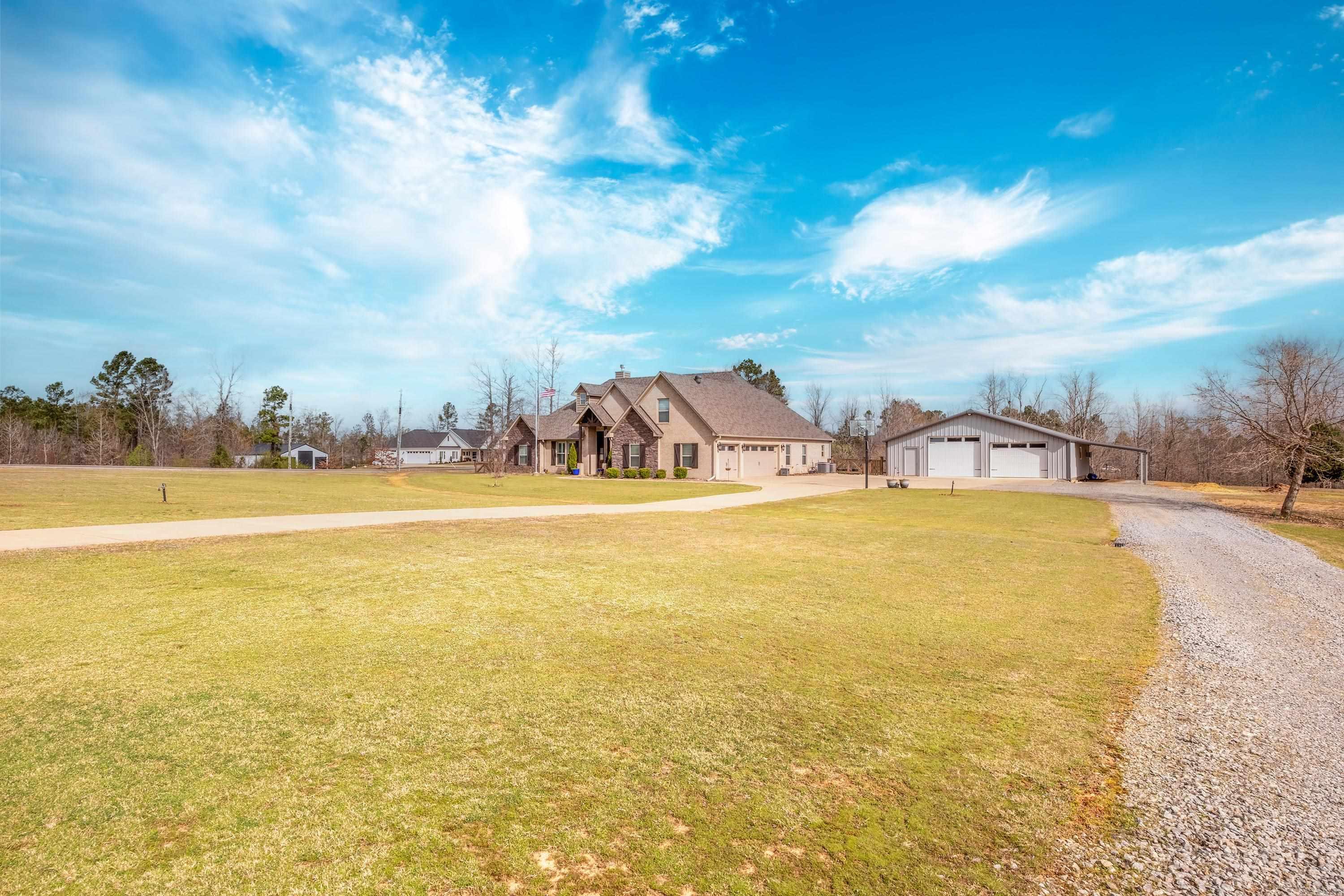 Enjoy this custom home and private outdoor space sitting on 3.25 acres. This stunning property welcomes you with double front doors leading to an open living room featuring a coffered ceiling and a floor-to-ceiling rock fireplace. Enjoy the view of the woods and natural light through large windows. The kitchen is a chef's delight with a pot filler, soft shut drawers, two pantries, and a large island. Downstairs, find two bedrooms with a Jack-n-Jill bathroom, an office, and a laundry room. The primary bedroom offers double-tray ceilings and an en-suite bathroom with a herringbone tile floor and marble countertop. Upstairs, an additional bedroom and bonus room with a full bath awaits. Outside, an insulated 50x40 metal frame shop with a half bath, laundry hookups, water fountain, heat and air, and an updated 9.5' garage door added. Updates include an upgraded septic system, new laminate and carpet, Roof (2023), new LED lighting, new electric stove, and a 18'x24'covered patio with new landscaping. Also features a 3-car garage and Fiber Internet. This home is ready for you to move in and enjoy!