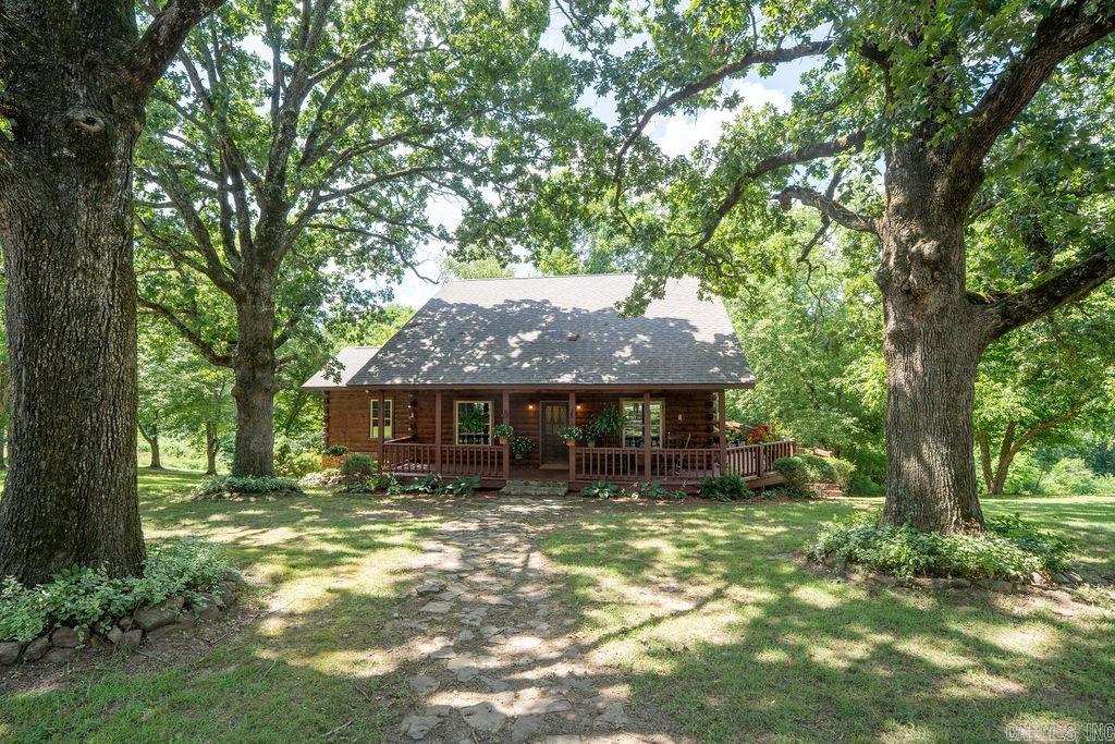 Located in a quiet, well kept neighborhood just 4 miles from the Stone County Courthouse Square in Mountain View and very convenient to the White River, this handsome log home with a wrap around porch is situated on gently sloping 1 acre tract and surrounded by an abundance of mature oak trees. The upper level has solid hickory wood floors, a large great room with vaulted ceiling and cozy gas log fireplace, a generous dining area, and a roomy kitchen. Also on the upper level is a nice size bedroom, a full bath with a whirlpool tub, and an office area. Downstairs the walkout basement features nine foot ceilings, a second living area and full kitchen, two bedrooms, a full bath, a laundry area, an additional room for hobby or office, and a private back porch. The 30x40 ft garage/shop has plenty of room for cars and toys with three bays, a built in workbench , and a large loft for extra storage. Built in 2006, this beautiful 2,612 sq ft home has been very loved and well maintained. Both the house and shop received a new roof in 2024 and the walkout basement received new tile and paint in 2024. All appliances convey. Watch the video!