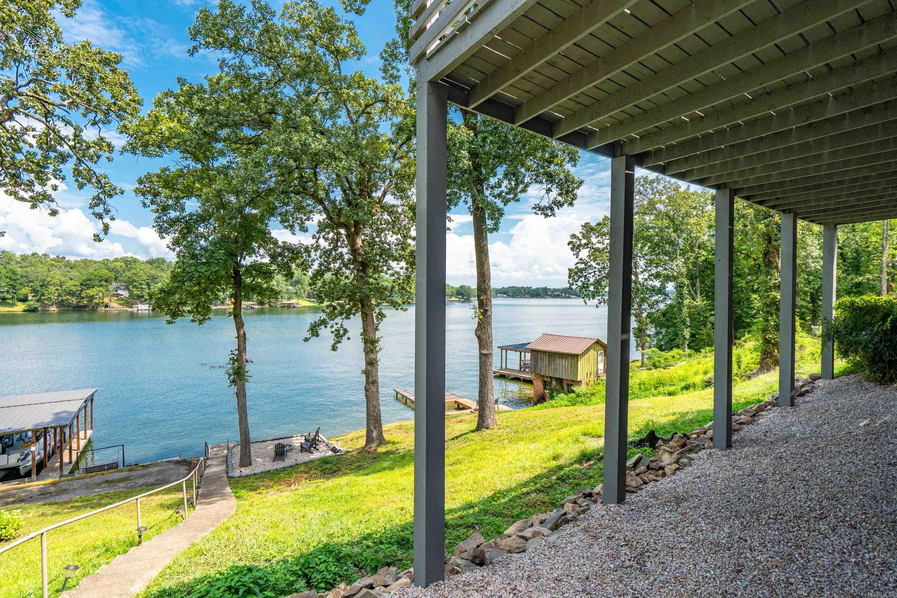 Rare find on Lake Hamilton! This fully renovated duplex sits on the main channel with year-round deep water and beautiful lake views. The upper unit offers 2 bedrooms, 2 baths, a modern open floor plan, and a spacious patio overlooking the water. The lower unit features 1 bedroom, 1 bath, an open layout, and an outdoor “man cave” perfect for entertaining. Property highlights include a circle drive, landscaped walkways, firepit rest area, small pier for lake access (no boat dock permit), and an additional off-road lot—ideal for boat parking or even building a guest house. Perfect for full-time living, a vacation retreat, or rental income. Don’t miss the virtual tour—call today to schedule your showing!