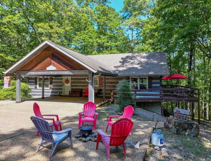 Discover your peaceful forest retreat in this inviting 3-bedroom, 3-bathroom one of a kind hewn log cabin nestled on a quiet cul-de-sac in Hot Springs Village. With high cathedral ceilings on the main floor, this fragrance-free cabin feels like a private mountain escape — and your perfect getaway.  Step inside to a chef’s-ready kitchen featuring sleek black granite countertops, flowing effortlessly into a spacious open living area with a cozy fireplace. The living area opens to a delightful wrap-around deck — your private front-row seat to deer sightings, birdwatching, or quiet family moments.  The main level hosts the luxurious master suite, complete with a king bed and spa tub ensuite, plus a guest suite with its own bathroom and shower. A bright sunroom awaits for meals or game nights with nature as your backdrop.  Downstairs offers additional sleeping space with three more beds and a full bath with shower. Outside, a firepit area with colorful seating invites you to toast marshmallows under the stars.  Located inside the gated Hot Springs Village, you’ll have access to 11 lakes, nine golf courses, a sand beach, marina, restaurants, and trails