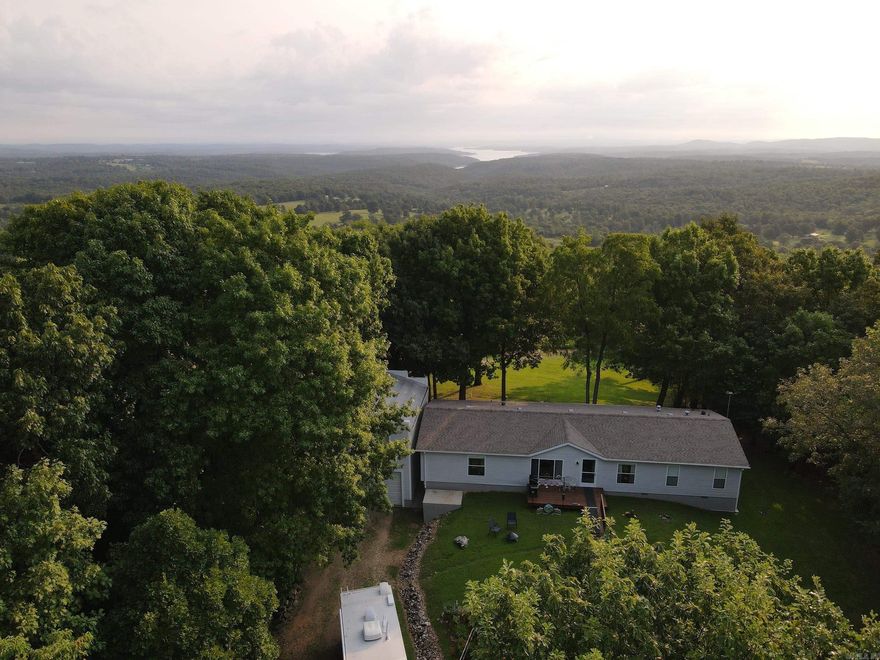 This phenomenal, wooded tract is loaded with privacy and charm. Overlooking Cave Hollow and Coon Creek both flow gently across the landscape like a blanket right into the famous Bull Shoals Lake. Setting atop the gorgeous, wooded tract is the impeccably kept modular home with three bedrooms, two bathrooms, open concept living/dining/kitchen, and all the charm you'd want. The home has recently been updated with new windows, flooring, bathrooms, and a fully added “man cave” for all your entertainment needs. Built on a partial basement, this home was set to never move and is in stunning condition. A whole home water filter system, newer A/C unit, updated roof, storm shelter, massive storage room, and roomy shop with two bay doors all come together like a dream. Every detail was well planned and put together to be sustainable, low maintenance, and enjoyable in every way. The manicured yard gently flows around the home to the opening in the timber for an absolute breathtaking view of the valley below and Bull Shoals Lake. The timber surrounding the home is large, mature, marketable, and all hardwood. The towering White Oak, Red Oak, Post Oak, Chinquapin Oak, Hickory, and Post Oak.