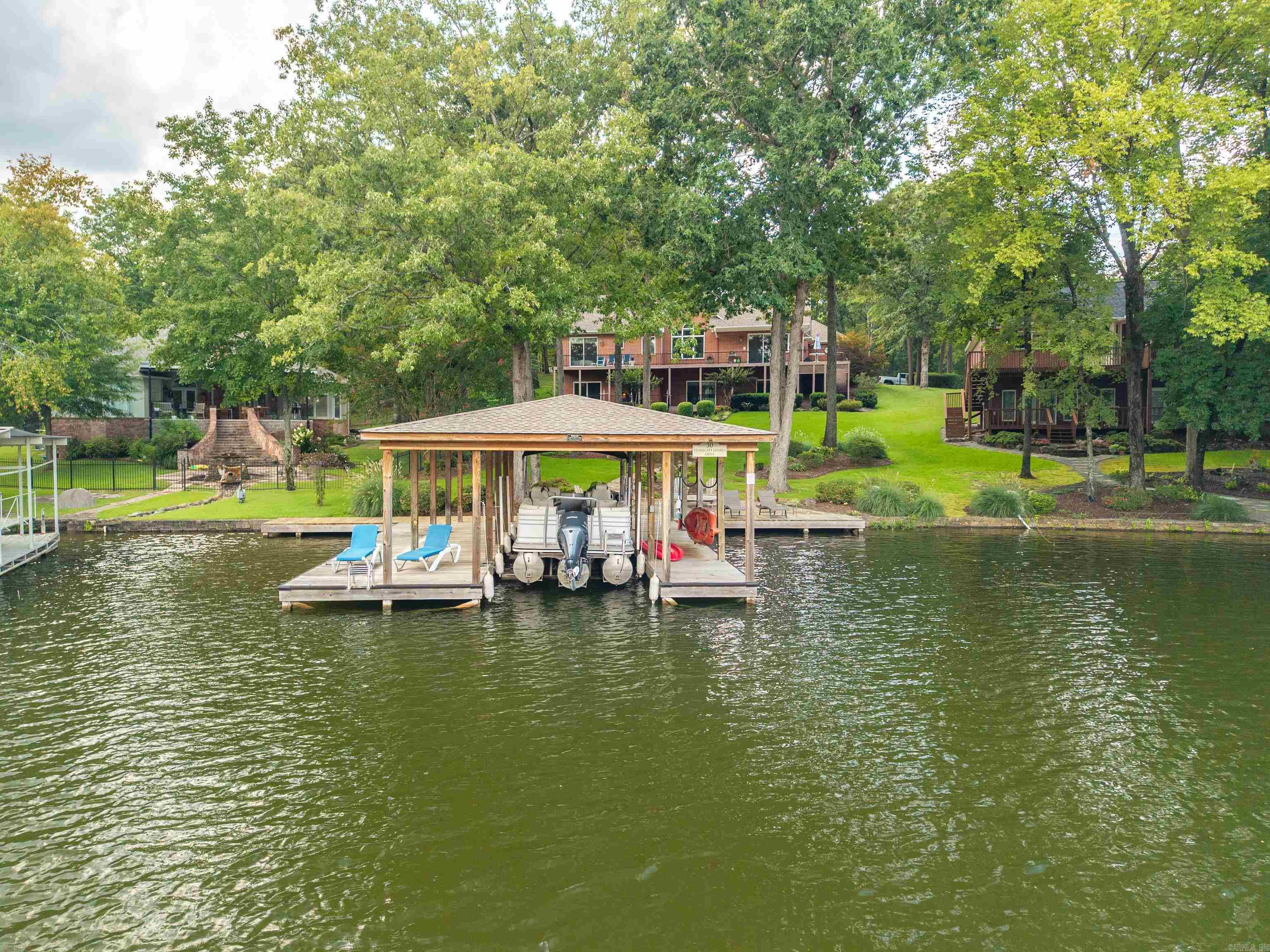 Offering the Best of Lakeside Living in Stonegate Shores Subdivision! This stunning 6-bedroom, 4-bathroom home is the perfect blend of luxury, comfort, & functionality! Step inside to discover a thoughtfully designed floor plan w/ large windows throughout filling the home w/ natural light & providing picturesque views of Lake Hamilton. The beautiful kitchen features high-end appliances, ample cabinetry, quartz countertops, a breakfast bar + eat-in breakfast area. The open layout flows seamlessly into the hearth room & dining area! The primary suite features a luxurious ensuite bathroom. There are 2 additional bedrooms on the main level, a full bathroom & fantastic laundry room! The lower level features 3 additional bedrooms, 2 full bathrooms, a 3rd living area + a game room! Whether you’re enjoying quiet time in the upper living space, cozy evenings by the fireplace in the hearth room, or family fun in the basement-level living space, this home was designed w/ versatility in mind. Step outside and take in the view from one of the numerous outdoor sitting areas, the lakeside patio, stationary boat dock & swim dock! Great location by land & water! Call today for a private tour!
