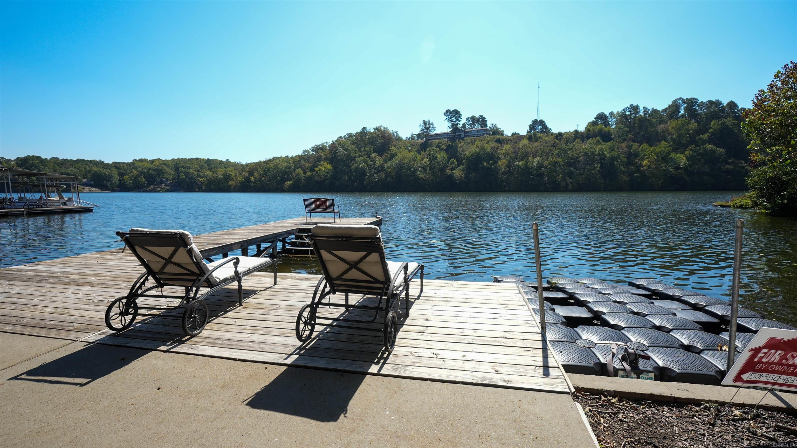 Lake living can't be beat and this home on Lake Catherine is calling your name! Sitting on nearly an acre, it is truly a private oasis like none other. This is a Completeley remodeled Hot Springs home with 105' lake frontage. This fabulous home was designed for entertaining. A screened in porch right off the family room will become one of your favorite spots for relaxing or you can sit in your lakeside sunroom with its gas stove on chilly evenings. The custom kitchen features an 8x5 1/2 granite island, custom cabinets and granite countertops. There is an abundance of storage in the laundry room pantry plus space for your freezer. Space for everyone with four bedrooms and three baths. A private drive takes you down to the lake with the seawall, shared boat ramp, boardwalk, deck, pation and a two stall boat house. Plenty of partking for all your guest. Brand new roof 11/22 and a full home generator.
