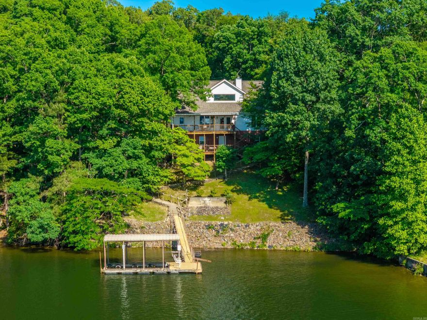 Welcome to 327 Longview Point — a truly rare opportunity on beautiful Lake Hamilton in Hot Springs, Arkansas. Nestled behind a private gated drive, this exceptional waterfront property offers over 5 wooded acres and approximately 400 feet of pristine shoreline with breathtaking full open-water views. This one-of-a-kind retreat features 3 bedrooms, 2.5 baths, and a dedicated office, combining comfort, privacy, and endless potential. The inviting living area is centered around a cozy fireplace and surrounded by stunning lake views, creating the perfect setting for relaxing or entertaining. The home also includes a basement area ideal for a workshop, storage, or future expansion. Enjoy direct access to Lake Hamilton with a one-stall covered floating boat dock. The private wooded setting offer sun matched seclusion while still being conveniently located in Hot Springs. With ample room for additional structures, guest homes, or future development, this property presents incredible possibilities for both personal enjoyment and investment potential. Properties like this rarely become available on Lake Hamilton. Investors take note — this is a legacy property with unlimited opportunity.