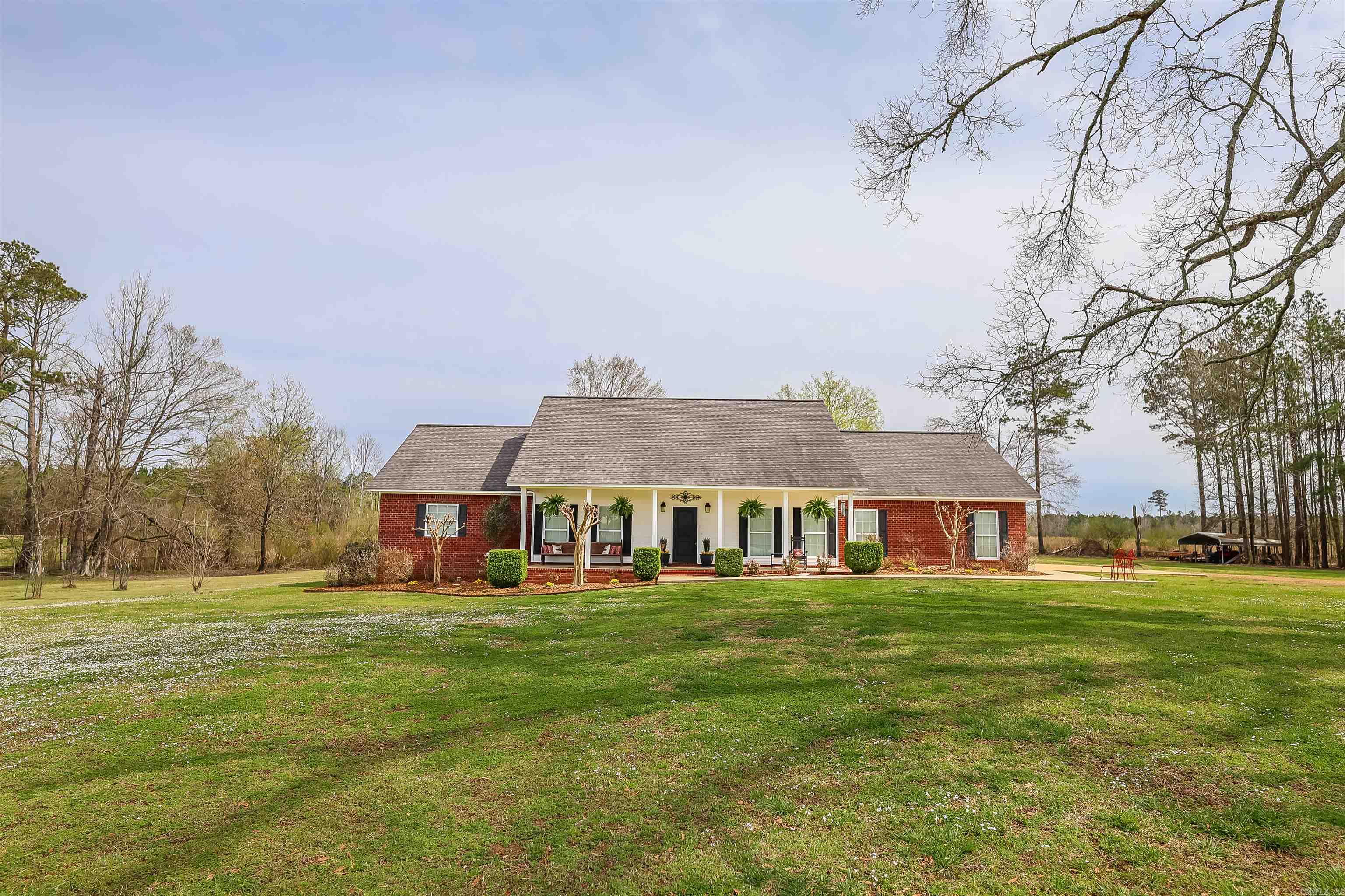 Country paradise! Sitting on 11 beautiful acres, this custom brick home offers an airy and well thought out interior. Quartz countertops grace the open concept kitchen, which is well-lit with over and under cabinet lighting. Don't miss the ample pantry! Gatherings are easy in the oversized living room which overlooks the covered back patio, complete with outdoor fireplace. Custom features include four en suite bedrooms, a half bath for guests, laundry room with exterior access, stained cement floors, and raised ceilings. Want the full rural experience? You'll love the stable, shop, and outbuilding, flanked with two fenced areas in the pasture. Make this one home today!