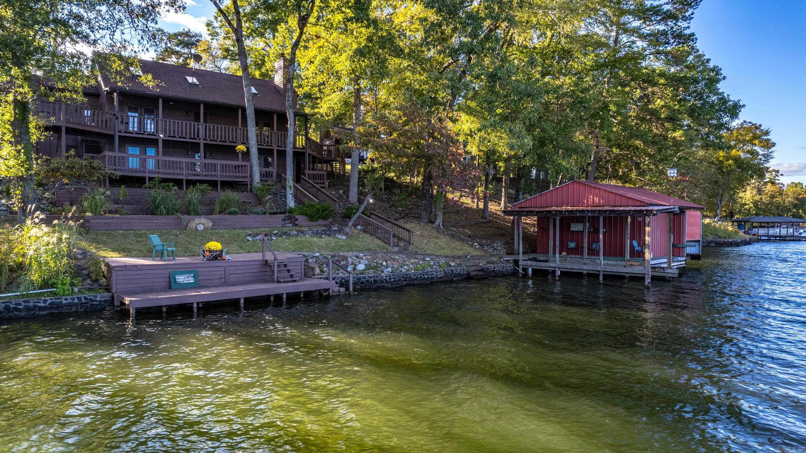 Charming - eclectic - rustic - one-of-a-kind...just a few of the words to describe your next residence. The nuts and bolts include 300 feet of Lake Hamilton shoreline on main channel. Post and beam construction with soaring ceilings and exposed beams and skylights allowing in the natural light. Original pine floors in living and dining areas. Geothermal heating system. Multi-level deck and outdoor gathering/entertaining spaces. Lake fed sprinkler. Enclosed boat house with lift and automatic door as well an attached 1 stall slip and small workshop area. The circle drive and parking pads coupled with the oversized 2 car garage means you’ll always have plenty of parking. 3 beds/2 bath with a bonus room that could be 4th bedroom as well an office space, this property will meet and/or exceed anyone’s needs whether it be owner occupy, vacation rental investment or both. Additional lot could also be developed or sold. Excellent opportunity to snag one that is priced to sell.