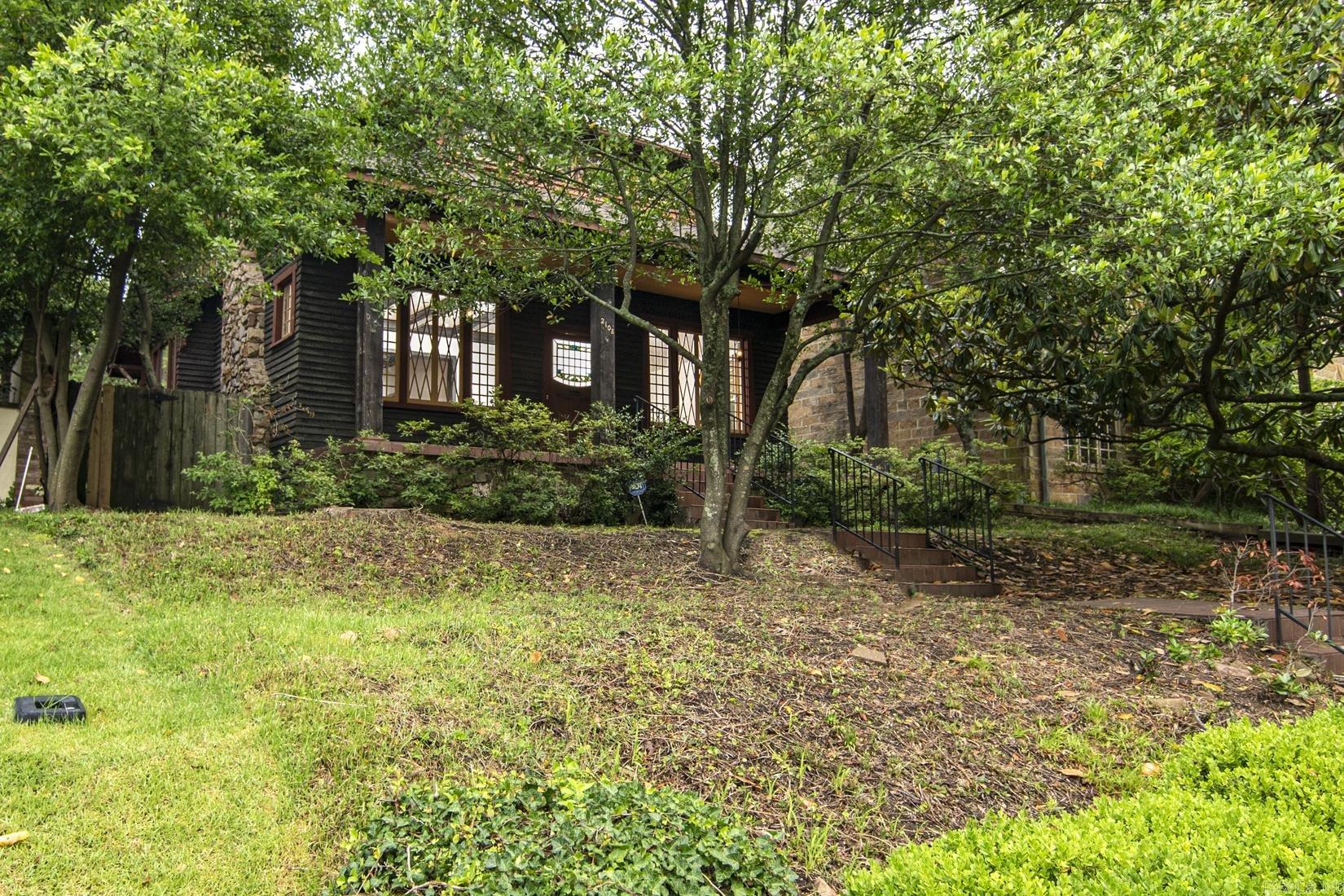 THE QUINTESSENTIAL HEIGHTS COTTAGE – One Block from the Country Club of Little Rock Built in 1912, this timeless home blends historic charm with thoughtful updates. A welcoming front porch with original windows and door opens to a warm interior featuring a cozy sitting room with original wood beams, built-ins, and fireplace. The living room flows into a spacious dining area with access to the kitchen, a secondary bedroom, and stairs to the upper level. The kitchen is ready for a custom renovation and leads to a second living area ideal as a den, playroom, or office. Two main-level bedrooms share a vintage-style bath. Upstairs, a large open room with en-suite bath offers flexibility as a primary suite, studio, or bonus space. Outside, enjoy a private fenced backyard, one-car garage, and two-car carport via rear alley. New Roof in 2025. Listed on the National Register of Historic Places, this home holds historic distinction without renovation or demolition restrictions.