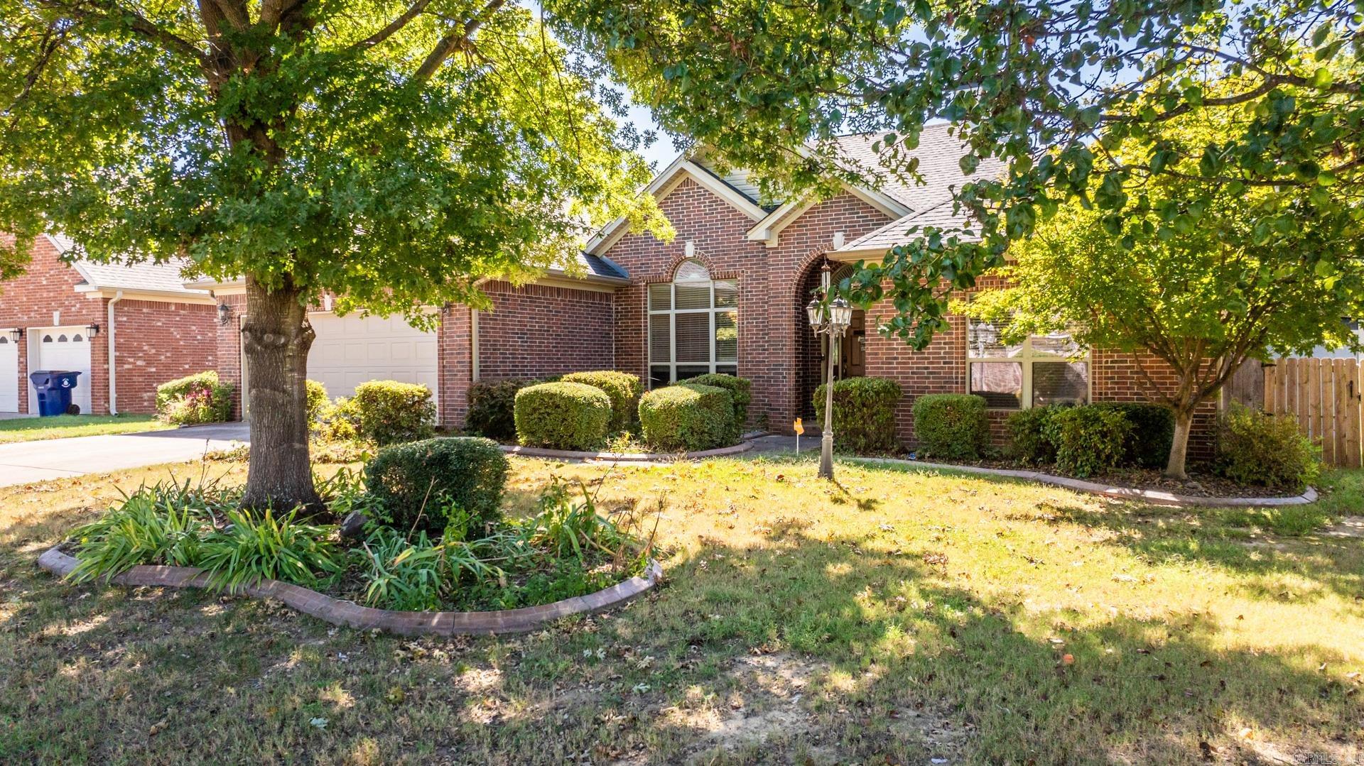 This beautiful all-brick, 4 BR home offers stunning landscaping and trees. Inside, enjoy 10 ft ceilings, a gas fireplace and beautiful hardwoods.  A beautiful 348 SF sunroom with its own HVAC is great for entertaining or just enjoying a good book. All bedrooms have walk-in closets. The primary suite is separate and features an 11 ft tray ceiling, double vanity, a jetted tub, and a separate shower. The kitchen has a new induction stove, new countertops, a large pantry and plenty of cabinets. There is a built-in desk in its own cove for working at home. Lots of windows bring in the sunshine. Extras with this home are a steel storm shelter, solar panels and generator.  The workshop has electricity and can be accessed from the front or back of the home. The large fenced backyard has a pergola and fire pit and easy access to walking trails.  Solar panels will be paid off at closing.