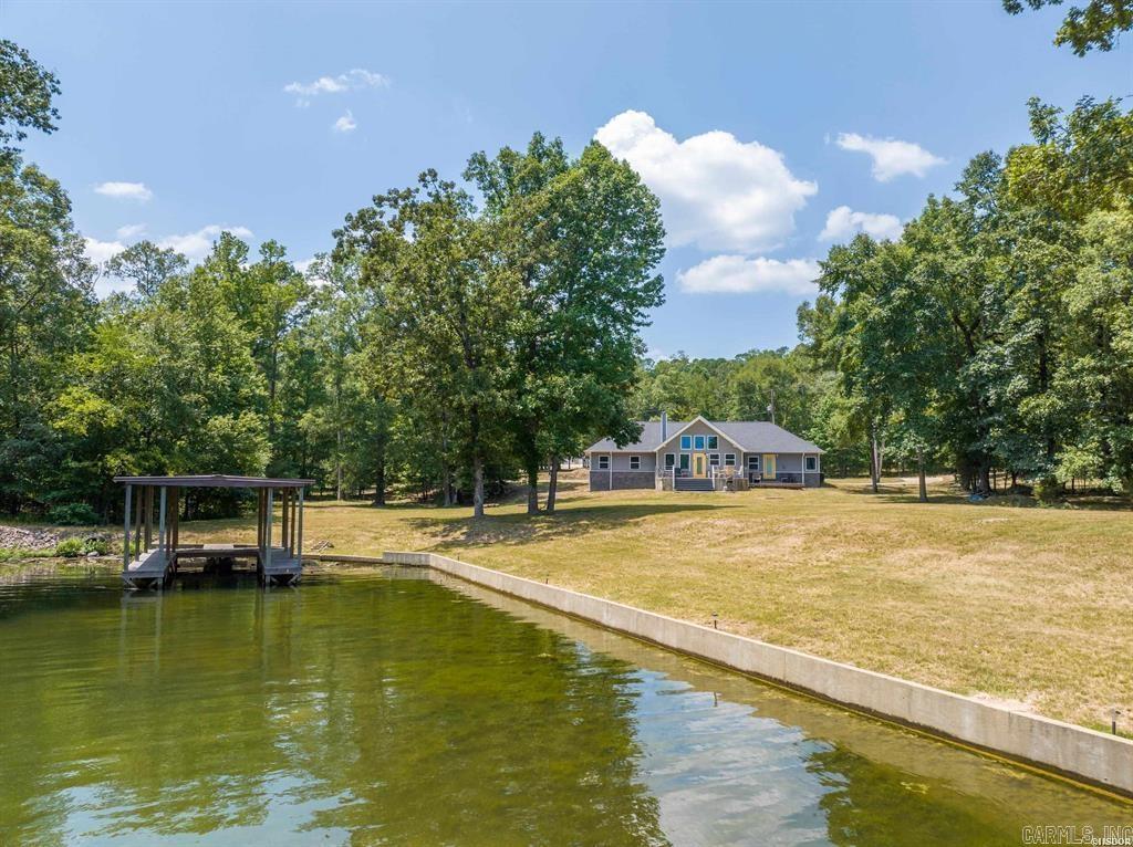 Welcome to this exquisite 2,218 sq. ft. lakefront retreat, perfectly situated on 3.17 acres with an impressive 337 feet of pristine shoreline along Lake Hamilton. Designed for those who appreciate the finest in lakeside living, this property offers a meticulously constructed seawall and two private boat docks—one with a covered single slip and the other featuring two slips—making water adventures a breeze.  Step inside to breathtaking panoramic views of the main channel, showcased through expansive floor-to-ceiling windows in the living room. The seamless integration of the open-concept chef’s kitchen and soaring 12-foot vaulted ceilings creates an inviting space, ideal for entertaining or simply soaking in the beauty of the surroundings.  The primary suite offers a tranquil retreat with private patio access, perfectly wired for a hot tub, where you can unwind while overlooking the serene lake. The spa-like master bath includes a luxurious whirlpool tub and a separate shower, creating the perfect oasis for relaxation.  This exceptional property offers limitless possibilities—whether as your primary residence, a vacation getaway, or a lucrative short-term rental investment.