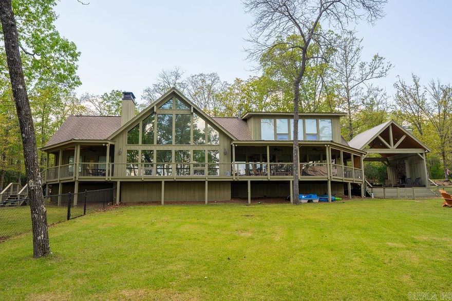 Lakefront luxury in Silver Shores at Tannenbaum, where architectural craftsmanship, wooded privacy, & effortless lake living come together. Set on an oversized, gently sloping lot w/easy shoreline access, this lodge-style retreat offers soaring vaulted wood ceilings, a dramatic wall of glass, & dual dry-stack stone fireplaces that anchor the open living and dining spaces. The chef’s kitchen features stainless appliances, a large island, & a well-designed butler’s pantry with abundant storage. The main-level primary suite includes its own stone fireplace, deck access, & tranquil wooded views, while a private guest suite & dedicated office add comfort & convenience. Upstairs, a spacious guest suite w/private bath provides ideal separation for family or visitors. Outdoor living is exceptional, w/a covered pavilion, wood-burning fireplace, wraparound decking, & fenced areas perfect for pets. Enjoy lake views from nearly every room, a 2-car garage w/storage, & close proximity to the community boat slip, nearby boat launch, & Tannenbaum Golf Club. This is a warm, inviting, and beautifully crafted lakefront home designed for gathering, relax & enjoying the best of Greers Ferry Lake.