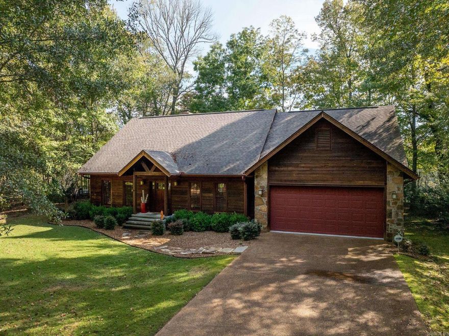 The Cow Shoals Cabin – Little Red River | Heber Springs, Arkansas  Welcome to the Cow Shoals Cabin, a truly special retreat perched above the Little Red River just outside the city limits of Heber Springs, Arkansas. Set on approximately 0.29 acres with about 120 feet of river frontage, this property sits within walking distance of the Arkansas Game and Fish Commission’s Cow Shoals access — and even features its own private staircase leading directly down to the river. Step out your back door and enjoy world-class trout fishing in your own backyard.  The cabin itself is as inviting as the view it overlooks. Spanning roughly 2,450 square feet, it features 3 bedrooms and 3 bathrooms, with an open layout designed to showcase the river from nearly every room. The living room’s floor-to-ceiling windows bring the water and sky right into the home, while a cozy sitting room with a stone fireplace creates a perfect space to unwind after a day on the river.  From the sitting room, step onto the screened-in porch overlooking the water, or head out to the 800-square-foot open-air stone patio — a natural gathering place for morning coffee or evening conversation as the river drifts by below.