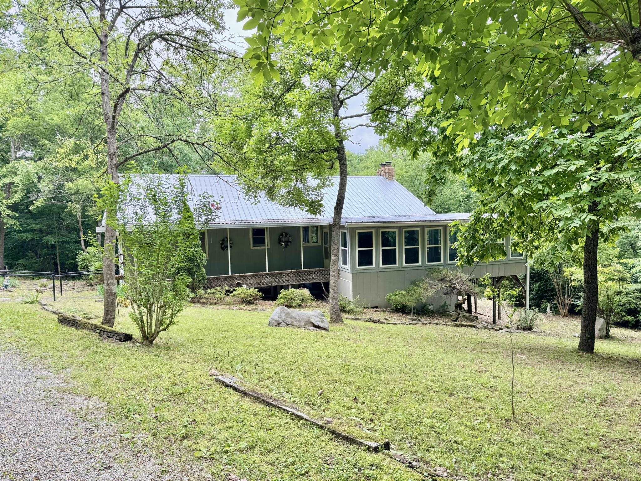 COUNTRY STYLE HOME IN THE OZARKS! Located on 4 acres just minutes from the White River. This charming 3-bedroom, 2-bath home offers a living area featuring vaulted ceilings and a cozy wood-burning stove along with a kitchen that has custom cabinetry and granite countertops. Downstairs, the full basement includes a spacious storage room or potential fourth bedroom, a second living area, and walk-out access. Enjoy peaceful mornings in the sunroom or entertain on the large back deck. This property has the ideal setting with privacy but close to the White River and Downtown Mountain View!