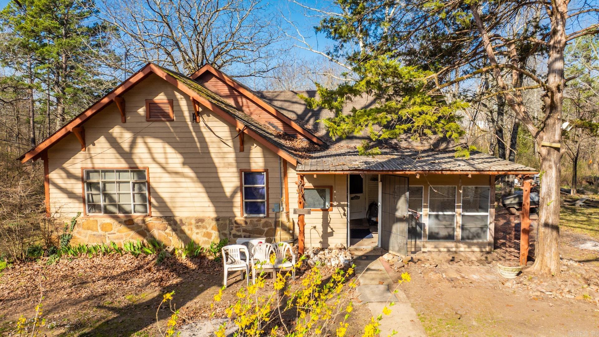 This quaint home in the country is tucked away off the road and has plenty of hardwoods on the property. The layout of the home has an open feel with an eat in kitchen and a well, three bedrooms, and plenty of flex space that can be used for hobbies. There are also four outside buildings that could be used as a she shed or man cave, studio, etc.