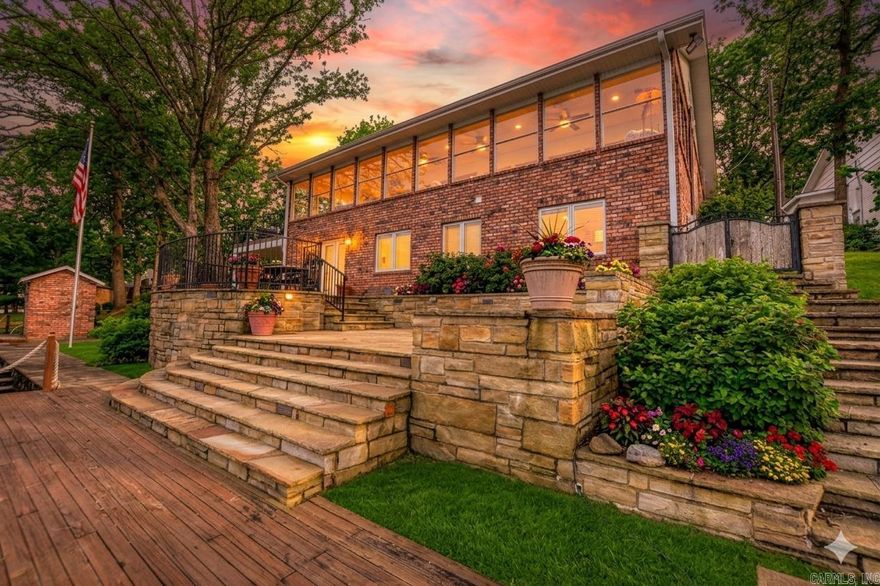 Situated on 95' of Lake Hamilton shoreline, this 4,200 SF brick estate offers a masterclass in lakeside luxury. Extensively renovated in 2023, the open-concept main level features hardwood floors and a gourmet kitchen with marble counters, a gas cooktop, and a wet bar with a brass sink. Walls of glass open to a full-length sun room with panoramic views and deck access. The main-floor primary suite includes a walk-in closet and a bath with a stackable W/D. The lower level offers four bedrooms, two baths, and a large laundry room, with French doors leading to a stone patio. Two additional bedrooms and a bath reside on the upper level.  Exquisite craftsmanship is found in every detail. The exterior is a waterfront paradise: a shoreline boardwalk, an oversized detached garage, and a premier boat dock (updated 2026) featuring two remote-controlled hydraulic lifts, two PWC slips, and a swim deck. Recent upgrades include a new roof and front windows (2023) and a new hot water tank (2026). Located in a quiet luxury enclave with no HOA, this home perfectly balances sophisticated design with lakefront utility.