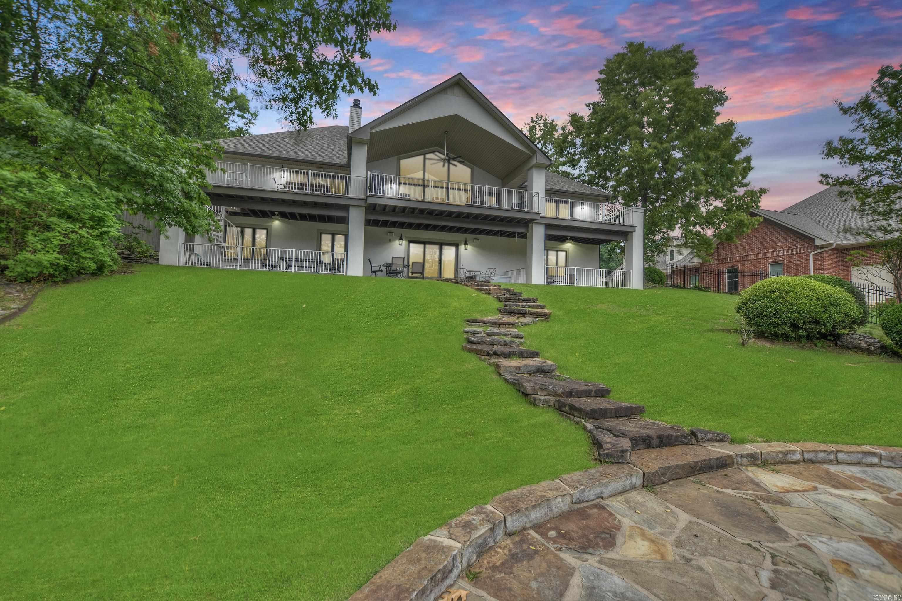 Modern 4,560 SF lakefront home with panoramic views in one of Hot Springs' most desirable neighborhoods. Features include triple-car garage, chefās kitchen with black granite & high-end stainless appliances, double-sided gas fireplace, and main-level primary suite. Walls of glass open to expansive deck; lower level offers 3 guest rooms, 2 baths, 2nd living area, kitchenette, wine storage, and walkout to covered patio & fenced dog run. Recent upgrades: new roof, gutters, exterior paint, carpet, and fencing (2024-2025). Includes 2-stall covered boat dock with hydraulic lift & PWC pad. Gated community with pool, clubhouse, tennis/basketball courts, boat ramp, and RV storage. No short-term rentals. HOA $700/yr.