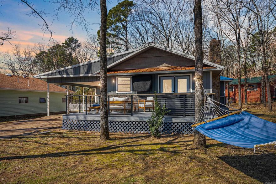 Each morning begins with a masterpiece—your cup of coffee paired with nature’s art gallery, as the sunrise paints a picture-perfect view over Sugarloaf Island & Greers Ferry Lake. This meticulously renovated home is a testament to a touch modern cabin elegance & timeless charm, Every room in this home, including bathrooms & kitchen, underwent a stunning transformation in 2023, ensuring a seamless blend of cabin style & cozy sophistication. The kitchen is equipped with all-new appliances in 2022, where you can prepare meals while savoring the mesmerizing view of Sugarloaf Island & the shimmering lake. The new Trex deck (2023) & front porch (2025) provide the perfect setting for entertaining & relaxation. Enjoy the ultimate "room" of the house...unwind in the new hot tub (late 2024), enjoy the fire table & TV to catch your favorite sports enveloped under a canopy of trees.  Distinguished by its interior finishes, all ceilings & wainscoat are either pine shiplap or blue ponderosa pine, & the pine interior doors of this home exudes warmth & distinction in every detail. A new metal roof was installed in 2024 ensuring durability for years to come. Furnishings $15,000. Hot tub conveys.
