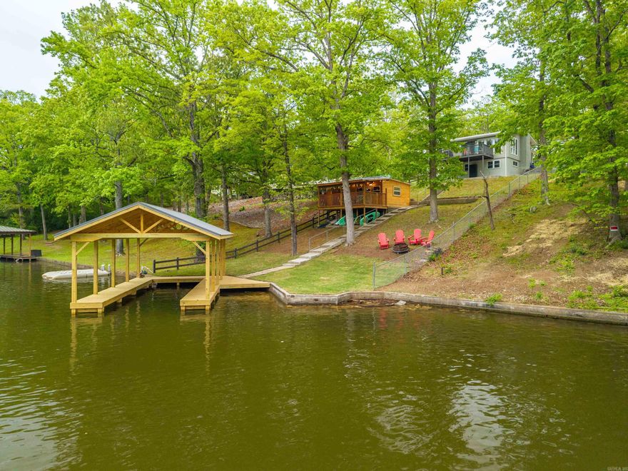 Experience a rare Lake Hamilton waterfront living opportunity combining luxury, privacy, and investment potential. This lakefront home boasts 50 ft. of prime shoreline in protected cove, offering fast access to open water and 280-degree lake views. This home features 3 BR. & 2 Bath, w/ a remodeled bathroom & bedrooms designed for comfort & style. Approx. 200 sq. ft. detached guest cabin in back that provides excellent flexibility for STR income, guest accommodations, or multi-generational living. Recently enhanced w/ a brand-new Entergy-permitted covered boat dock, seawall, & PWC slip, making it ideal for lake recreation. Brand-new landscaping in both the front and backyard creates a resort-like outdoor setting. Situated on a quiet, closed-loop road, this home offers a peaceful, private atmosphere while remaining close to downtown Hot Springs, dining, & attractions. Outdoor enthusiasts will love direct Lake Hamilton access & close proximity to Lake Ouachita, delivering unmatched access to boating, fishing, hiking, & nature. Whether you’re seeking a luxury primary residence, vacation home, or high-performing STR investment, this property checks all the boxes.