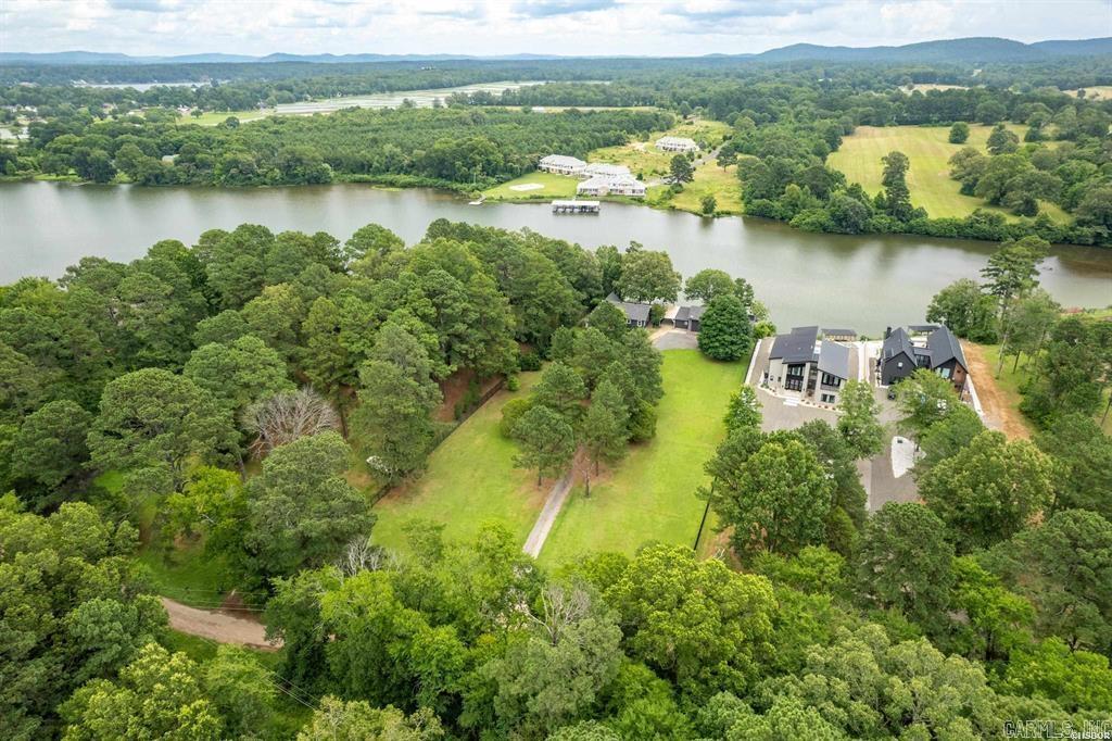**Absolutely Unique Lakeside Retreat with Country Charm and Luxury!** 1.58 acres of your own private oasis awaits! Step into a residence that feels like it jumped straight out of a Martha Stewart magazine! Nestled on the serene shores of Lake Hamilton, this stunning property beautifully combines country charm with modern luxury. Perfect for those seeking to get away from the bustle of everyday life, this home offers both relaxation and sophistication. In fact you may never want to leave! The main house features 2 spacious bedrooms and 2.5 bathrooms, designed to provide comfort and tranquility. The open-concept living space invites natural light with its expansive windows, showcasing breathtaking lake views while highlighting custom finishes throughout. Features include vaulted wood ceilings, wood flooring and a wood burning fireplace. Just imagine sipping your morning coffee on the deck as you watch sunrises light up the water! The kitchen will take your breathe away with a large custom island breakfast nook and adorable modern country feel. Downstairs you will find a half bath and partially finished space currently used as a home office. Cont'd in Agent Remarks...