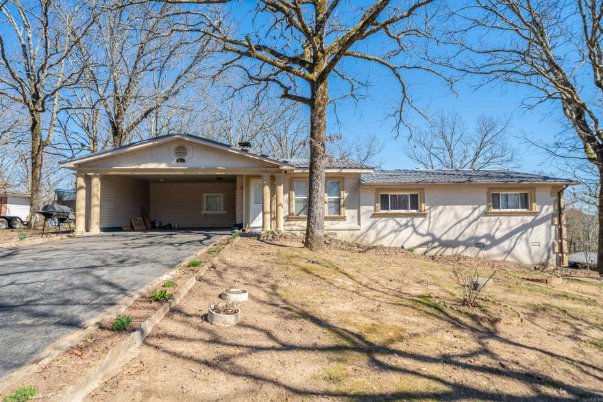 Welcome to this charming ranch-style home located in the highly sought-after Lake Hamilton School District. This spacious 4-bedroom, 3-bathroom property offers a great blend of potential and updates, with room to make it your own. The living room boasts a stunning stone fireplace, creating a cozy focal point for the space. A partial kitchen remodel has already begun, with some new cabinets and beautiful butcher block countertops, setting the stage for your personal touch to complete the space. The home features two living areas, providing ample room for relaxation and entertaining. The bathrooms have been updated, adding a fresh and modern touch to the home. Outside, enjoy a large back deck that overlooks the fenced backyard, perfect for outdoor gatherings or quiet relaxation. The 2-car carport and durable metal roof add to the home's practicality and appeal. This property offers a fantastic opportunity for those looking to personalize a home in a prime location. With a little finishing touch, this house can be transformed into the perfect home. Don't miss your chance to make it yours!