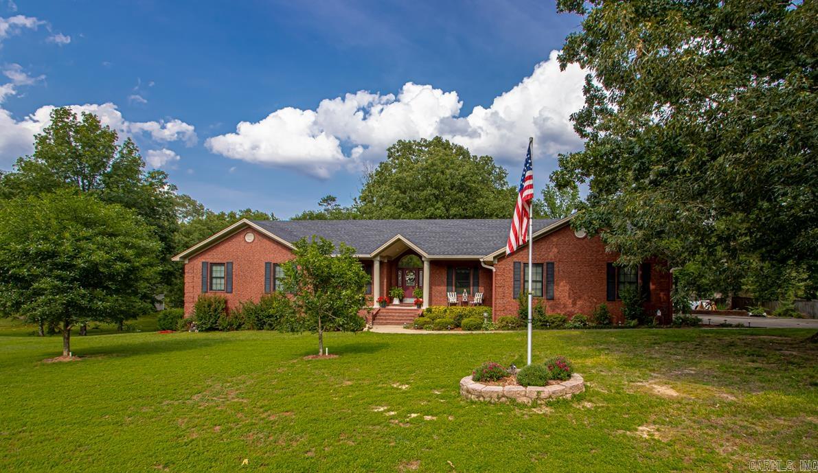 Immaculate 4 BR/3 Ba home on 2 acres in Country Oaks Subdivision! Spacious kitchen with 10 foot island, perfect for entertaining. Beautifully landscaped, tree-shaded lot with a screened-in back porch for relaxing outdoors. Side-entry garage, full-house generator, encapsulated crawlspace, and abundant storage throughout. Property includes 31 X 53 foot detached outbuilding, with 2 bay doors-ideal for a workshop, or boat storage. Home does have 26 X 23 foot under house for workshop or storage. Home sits on two lots in a quiet, well-maintained neighborhood just 2 minutes from downtown. Light, airy floor plan and pride of ownership shine throughout. Home does offer a home office perfect for todays, work from home lifestyle. Located 30 minutes from Hot Springs National Park.