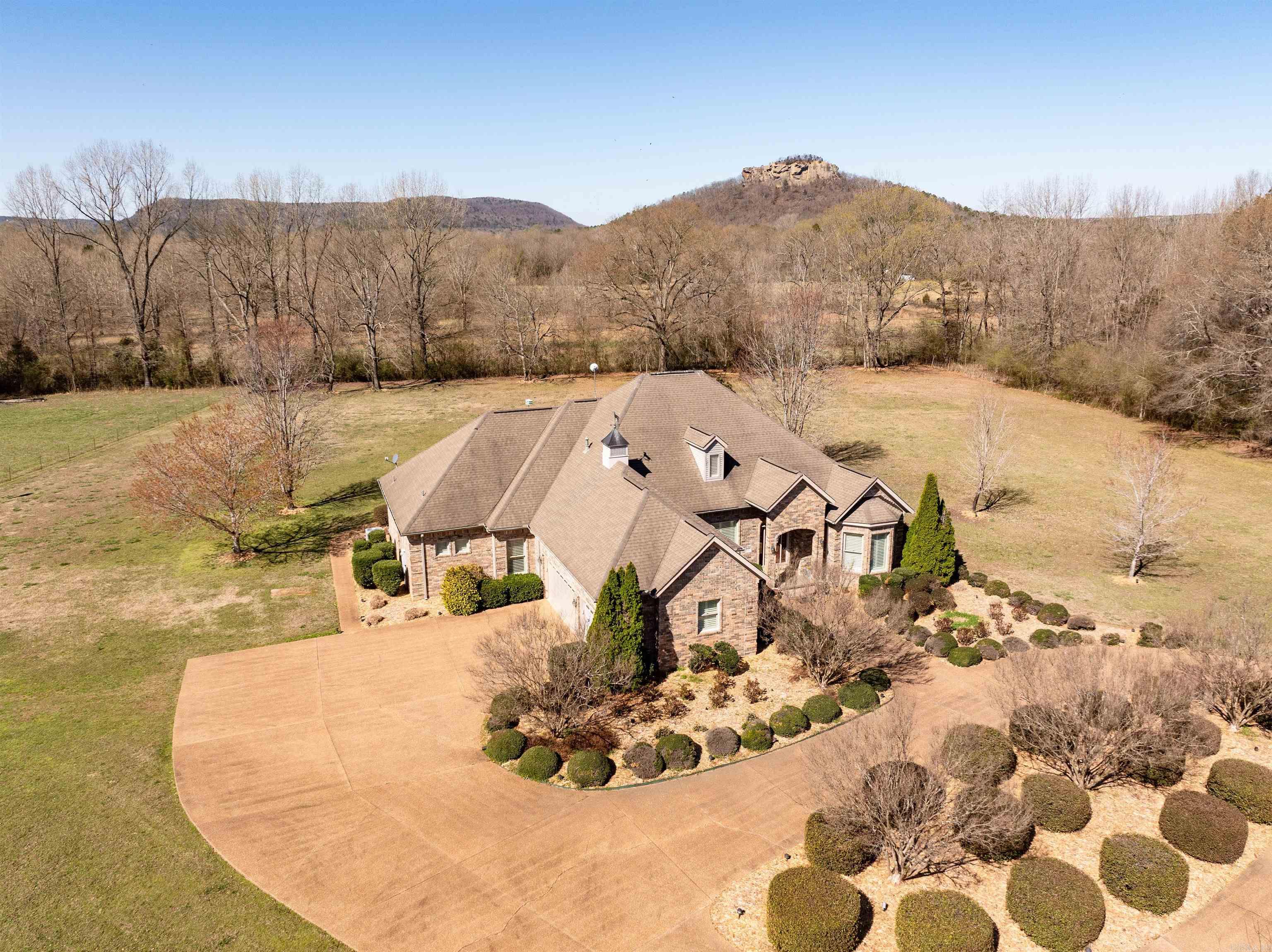 Refined Southern Living on 30 Unrestricted Acres Just minutes from the river and lake, this one-level 2,851 SF brick estate offers privacy, elegance, and versatility. The main home features 3 bedrooms (2 primary suites), 3.5 baths, formal living and dining, office, and an open kitchen/den with fireplace. High-end finishes include wood floors, granite counters, plantation shutters, and a bar. The property also includes a 1-bedroom guest cottage, two barns/shops, ponds, pasture, Sugarloaf Mountain views, and frontage on both Hwy 110 E and River Trail. A 2-car garage, golf cart garage, circular drive, and city water access round out this rare opportunity—ideal as a private estate, retreat, or future development site.