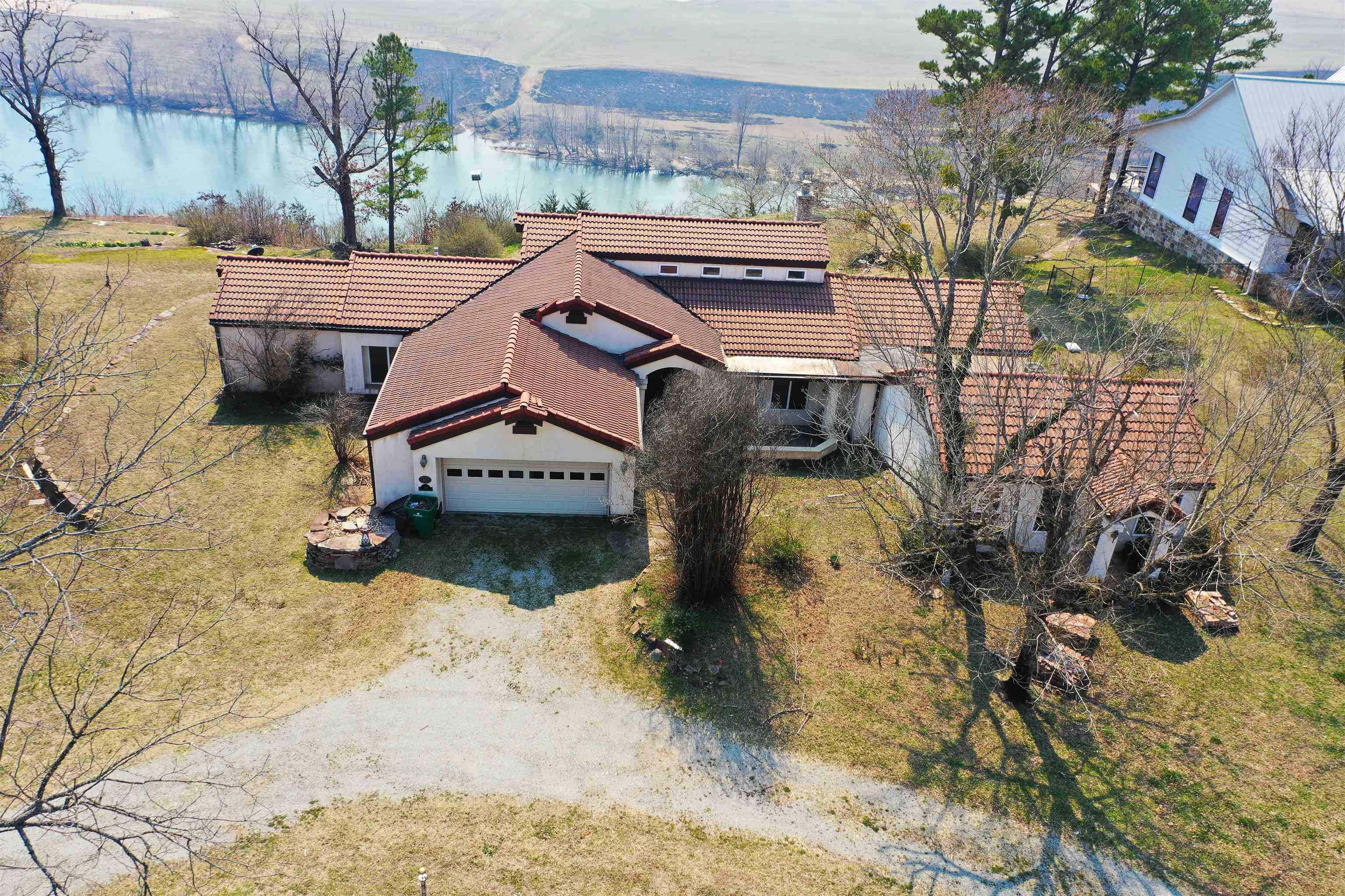 Nestled atop a majestic bluff overlooking the beautiful White River. Step into this stunning 3-bedroom, 2 full & 1 half-bath, with over 2,400 sq ft of living space. This architectural design features a unique Spanish style home with a tile roof and unbelievable views. Spanish tile floors throughout a large portion of the house. Open floor plan seamlessly connecting the living, dining and kitchen areas. A cathedral style living room with arched and framed openings for your own special design. A kitchen with two pantries offers both functionality and ample storage. The 4th bedroom/office with built-in bookshelves is a relaxing place to work. A private wing office with built-in shelving and storage and over 600 sq ft work area and its own private bathroom. Between the private office and full bath is a safe room. Panoramic view awaits you from 5 double doors coming off the back of the house onto the stone patio. Attached 2-car garage with access to the attic.