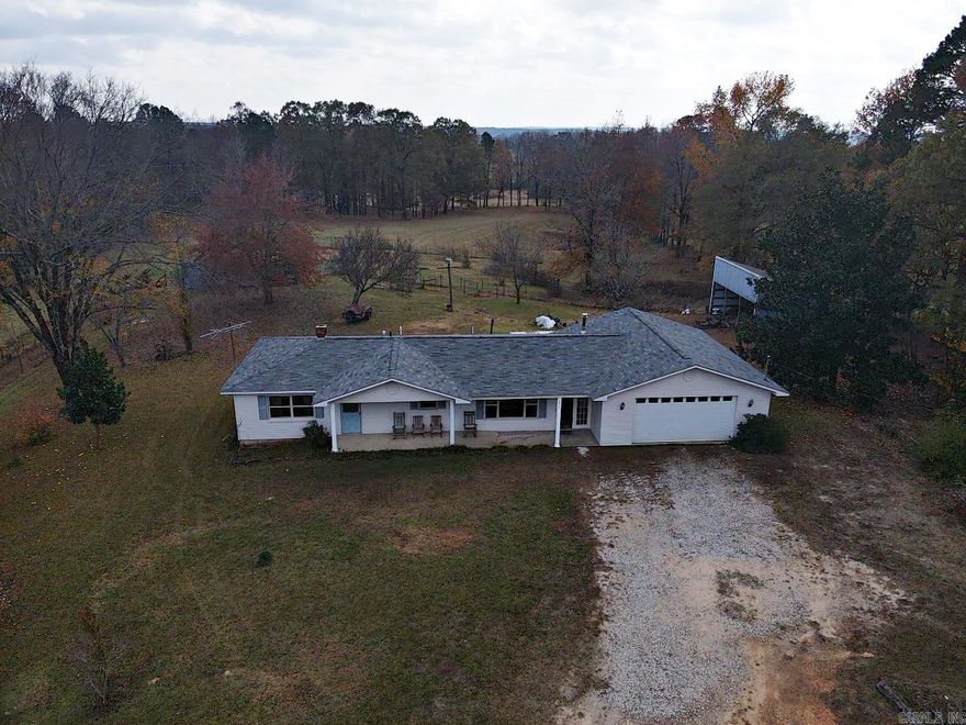 On this beautiful property is the 1300 sq ft home listed in this description as well as a 1024 sq ft 3/2 mobile home, set up and fully functioning, plus a 60 X 30 metal shop.  It is great for a big family or for rental income in the future. The concrete block home has insulation inside the blocks making utilities very low.  The 2-car garage is heated by a wood stove and is attached to the house with an enclosed dog trot passageway.  The wood stove from the garage is piped over into the house for heat. The shop has 2 bay doors and lots of room for any type of work. The covered back porch and additional shed look out over the acreage. Located close to all surrounding towns, this is a real gem of a property.  It is ready to be brought up-to-date or is great as it sits.  The property is sold "as is." Call for a showing today.  See agent remarks.